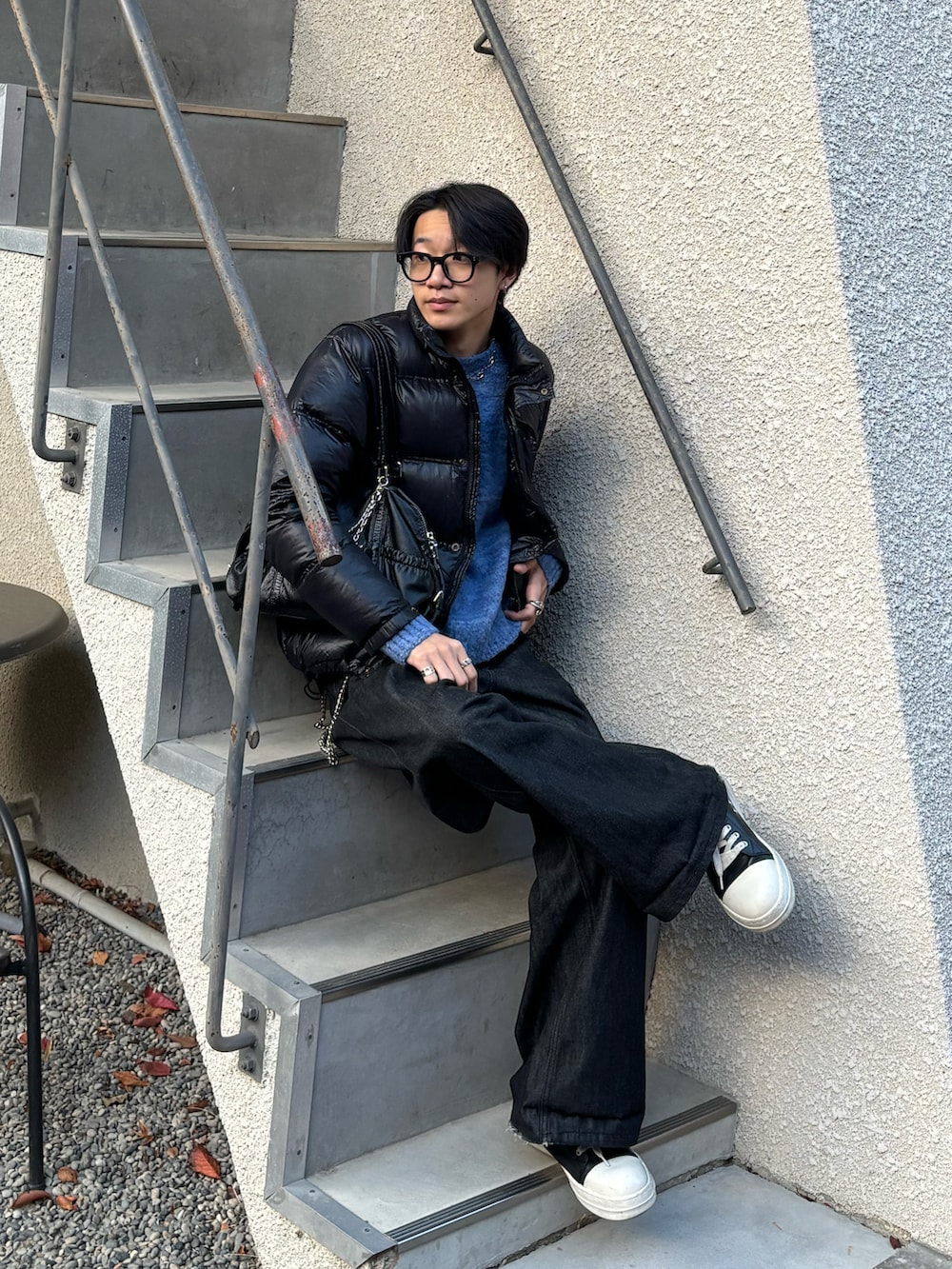 ブラック系のダウンジャケット/コート、ブルー系のニット/セーター、ブラック系のデニムパンツを着用したメンズの冬コーディネートの2枚目の写真