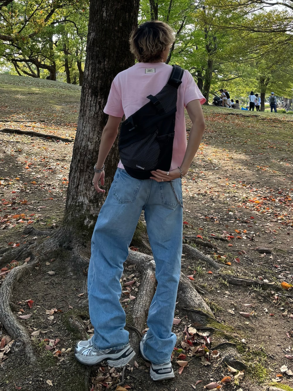 ピンク系のTシャツ/カットソー、ブラック系のショルダーバッグ、ブルー系のデニムパンツを着用したメンズの春コーディネートの2枚目の写真