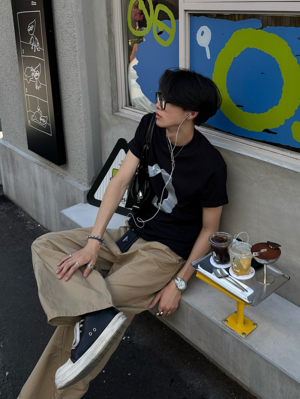 ブラック系のTシャツ/カットソー、ブラック系のショルダーバッグ、ベージュ系のチノパンツを着用したメンズの夏コーディネートの4枚目の写真