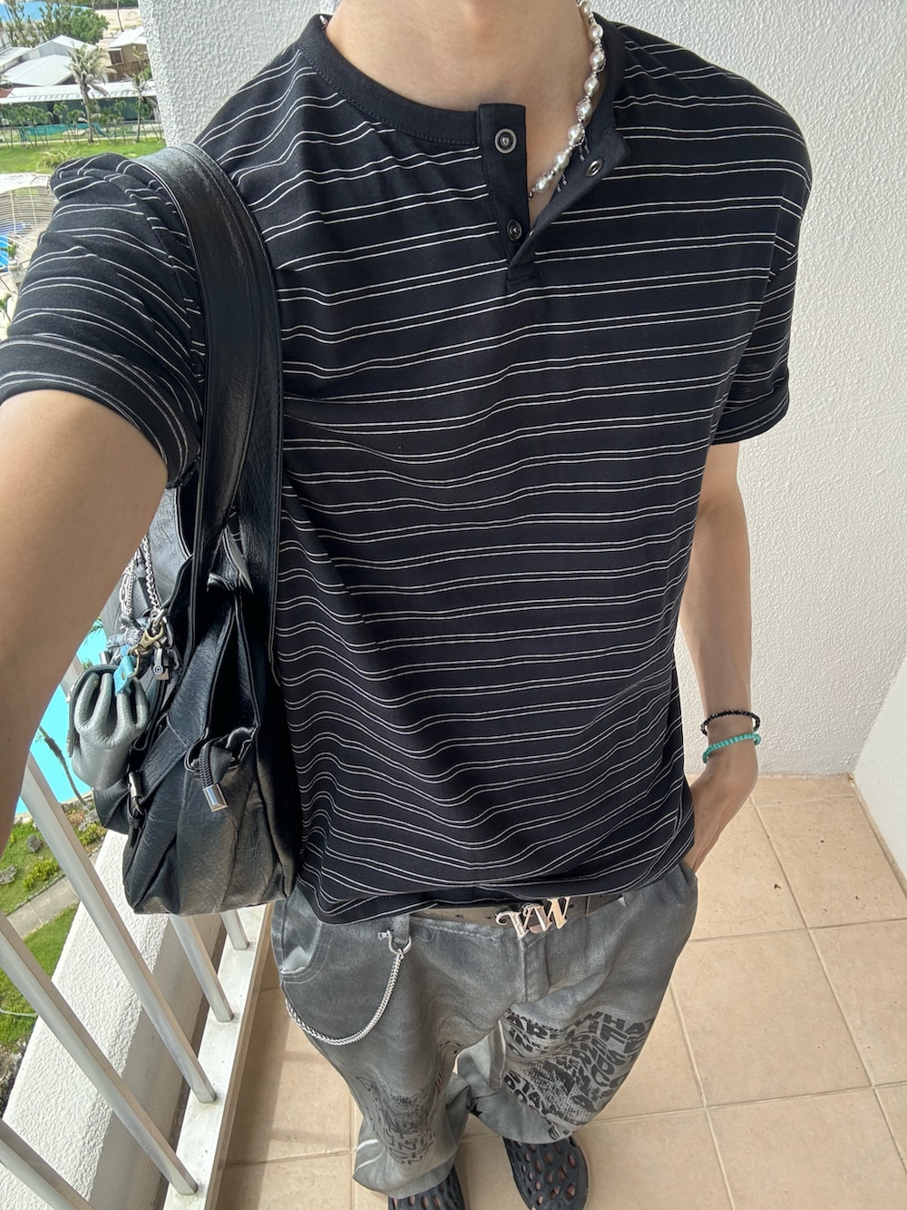 ブラック系のTシャツ/カットソー、ホワイト系のデニムパンツ、ブラック系のサンダルを着用したメンズの夏コーディネートの5枚目の写真