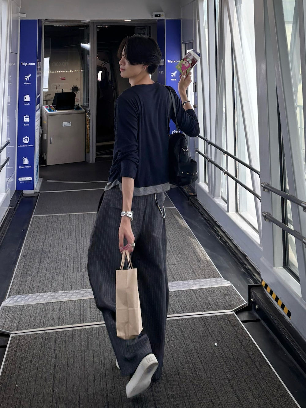 ブルー系のTシャツ/カットソー、グレー系のスラックス、ブラック系のスニーカーを着用したメンズの秋コーディネートの5枚目の写真