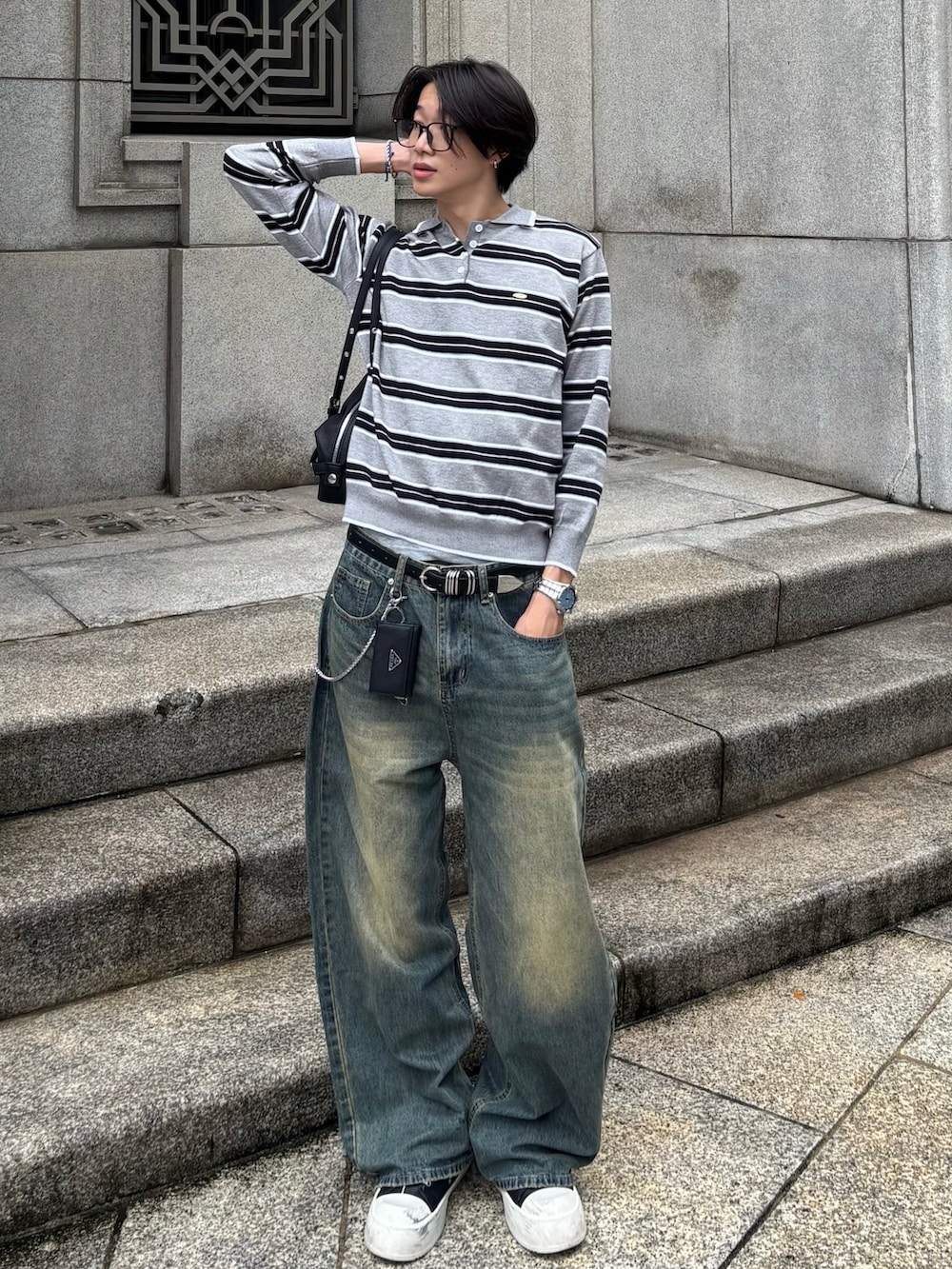 グレー系のニット/セーター、ブルー系のデニムパンツ、ブラック系のスニーカーを着用したメンズの秋コーディネートの2枚目の写真