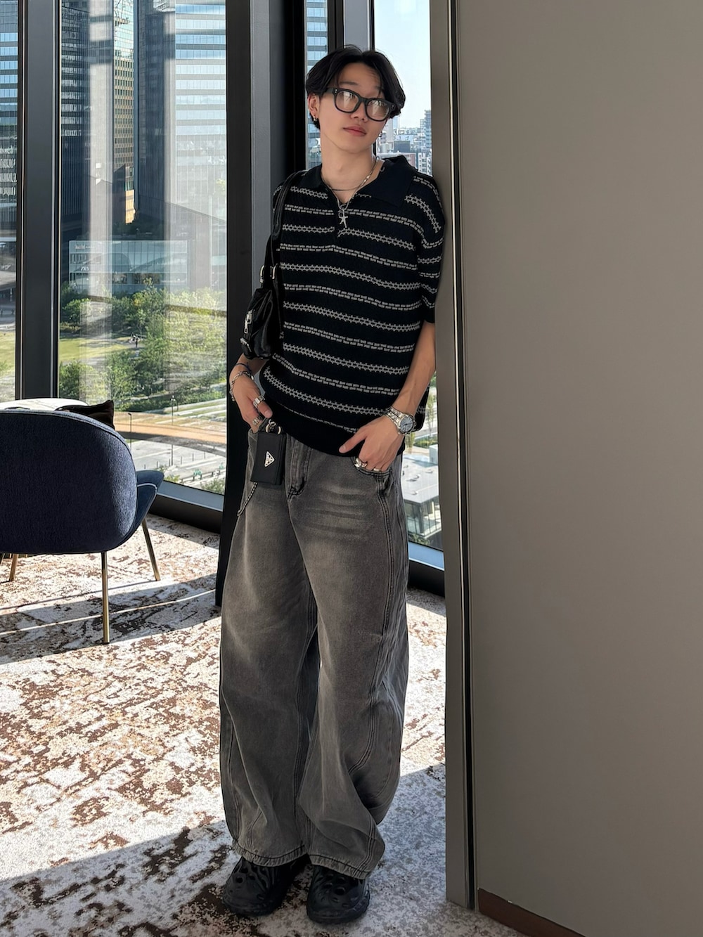 ブラック系のポロシャツ、グレー系のデニムパンツ、ブラック系のサンダルを着用したメンズの春コーディネートの3枚目の写真