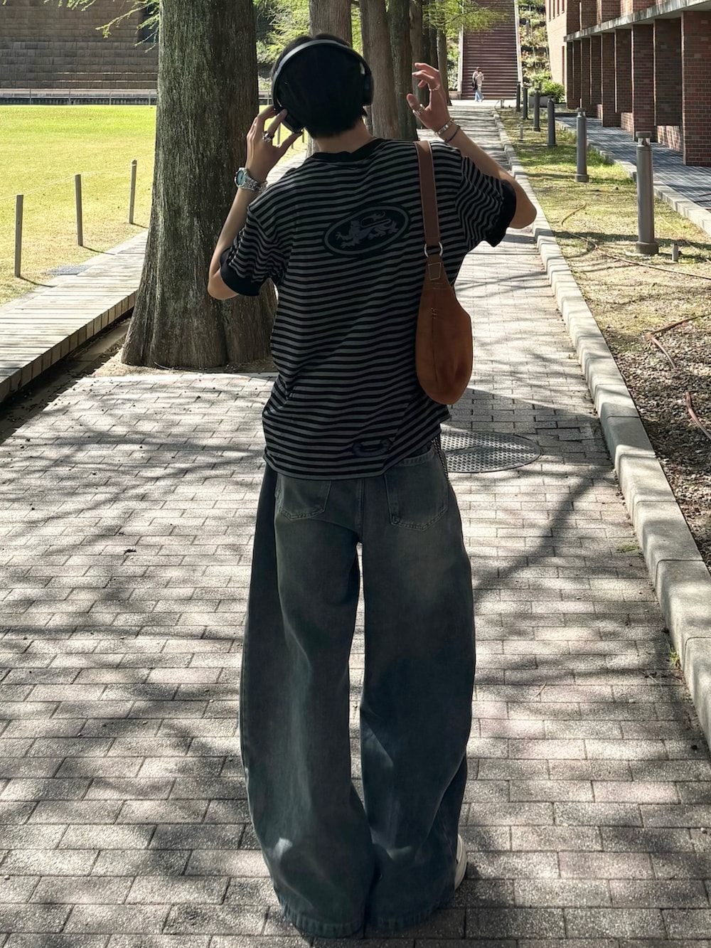 ブラック系のTシャツ/カットソー、ブルー系のデニムパンツ、ブラック系のスニーカーを着用したメンズの春コーディネートの2枚目の写真