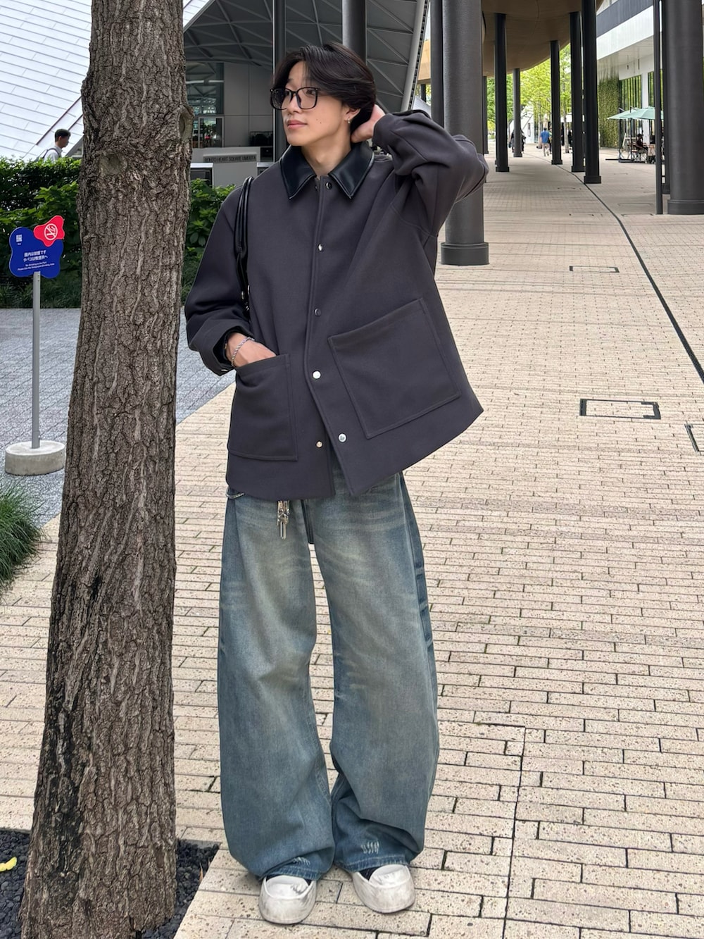 ブルー系のデニムパンツ、ブラック系のスニーカー、グレー系のステンカラーコートを着用したメンズの秋コーディネートの2枚目の写真
