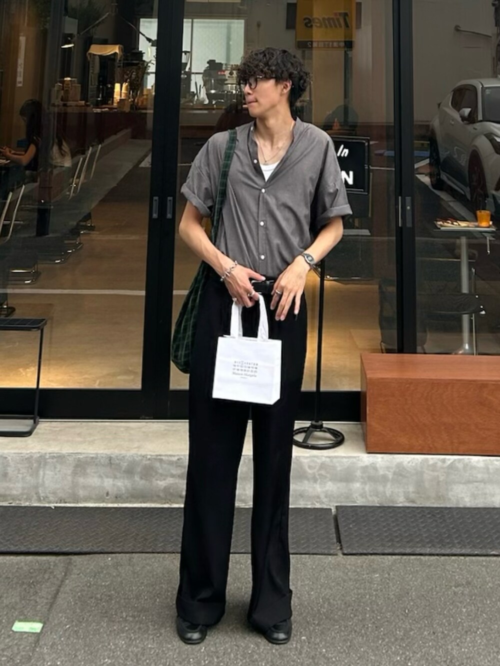 グレー系のシャツ/ブラウス、グリーン系のトートバッグ、ブラック系のスラックスを着用したメンズの春コーディネートの2枚目の写真