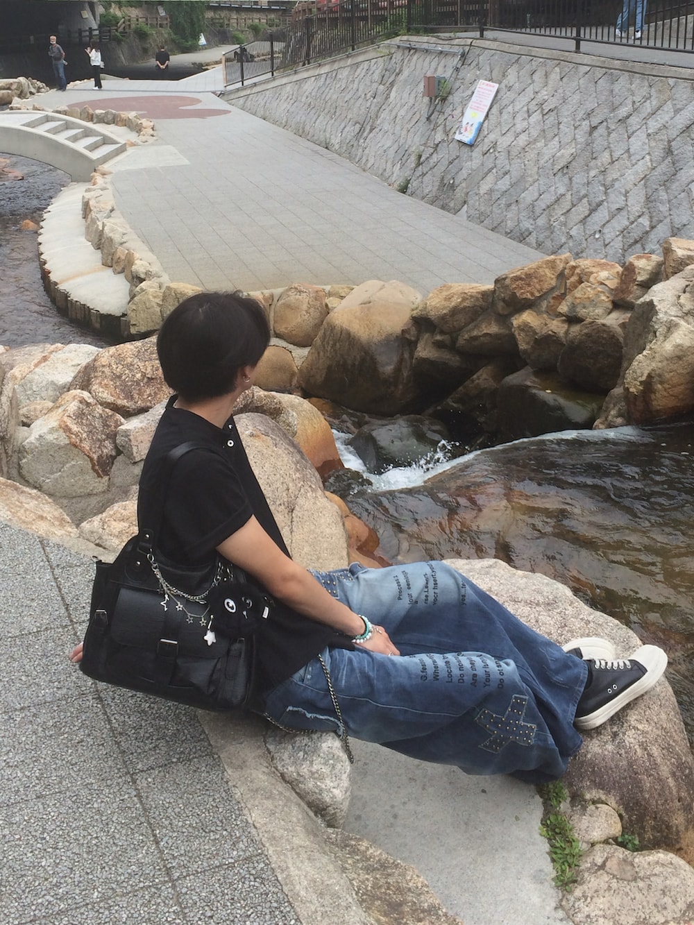 ブラック系のTシャツ/カットソー、ブルー系のデニムパンツ、ブラック系のスニーカーを着用したメンズの夏コーディネートの3枚目の写真