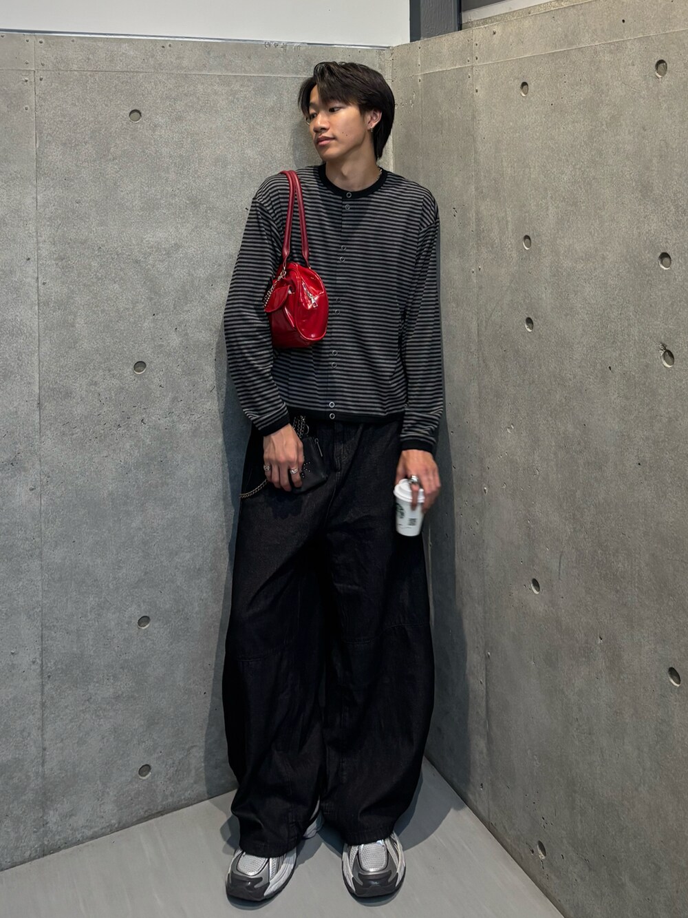 ブラック系のカーディガン/ボレロ、レッド系のトートバッグ、ブラック系のデニムパンツを着用したメンズの秋コーディネートの2枚目の写真