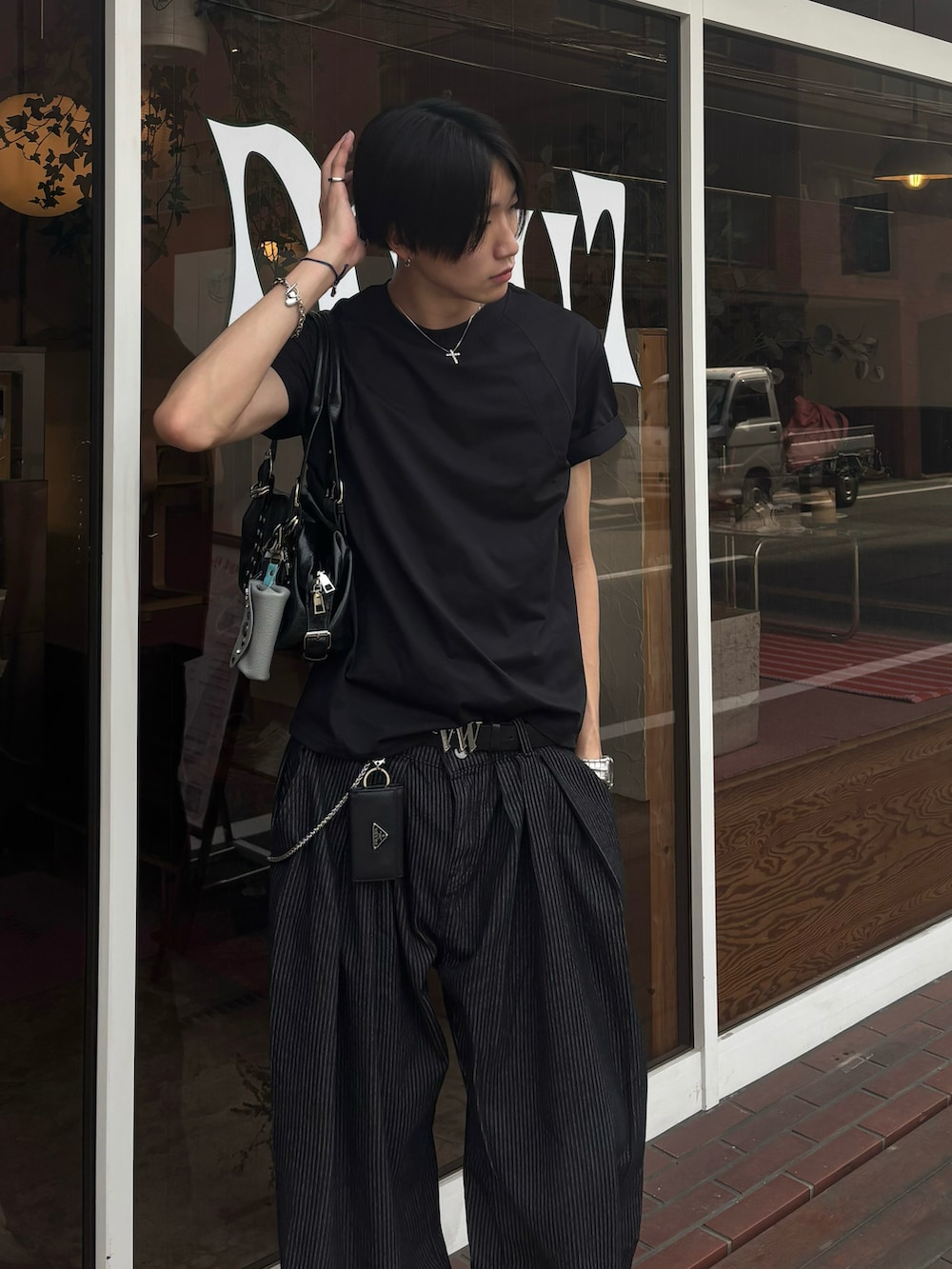ブラック系のTシャツ/カットソー、ブラック系のスニーカー、ブルー系のデニムパンツを着用したメンズの夏コーディネートの4枚目の写真