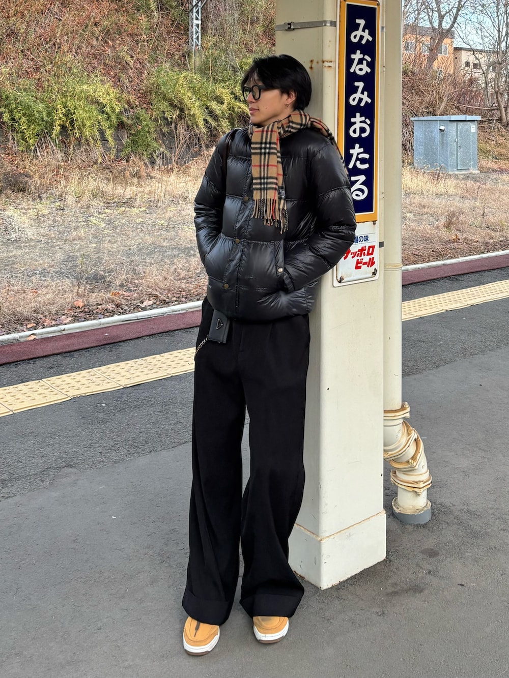 ブラウン系のショルダーバッグ、ブラック系のスラックス、イエロー系のスニーカーを着用したメンズの冬コーディネートの4枚目の写真