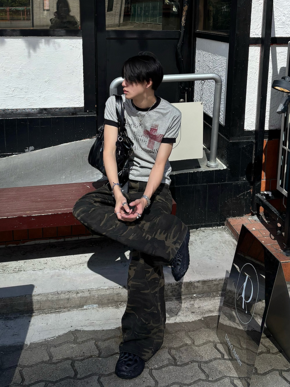 グレー系のTシャツ/カットソー、ブラック系のショルダーバッグ、その他のデニムパンツを着用したメンズの春コーディネートの2枚目の写真