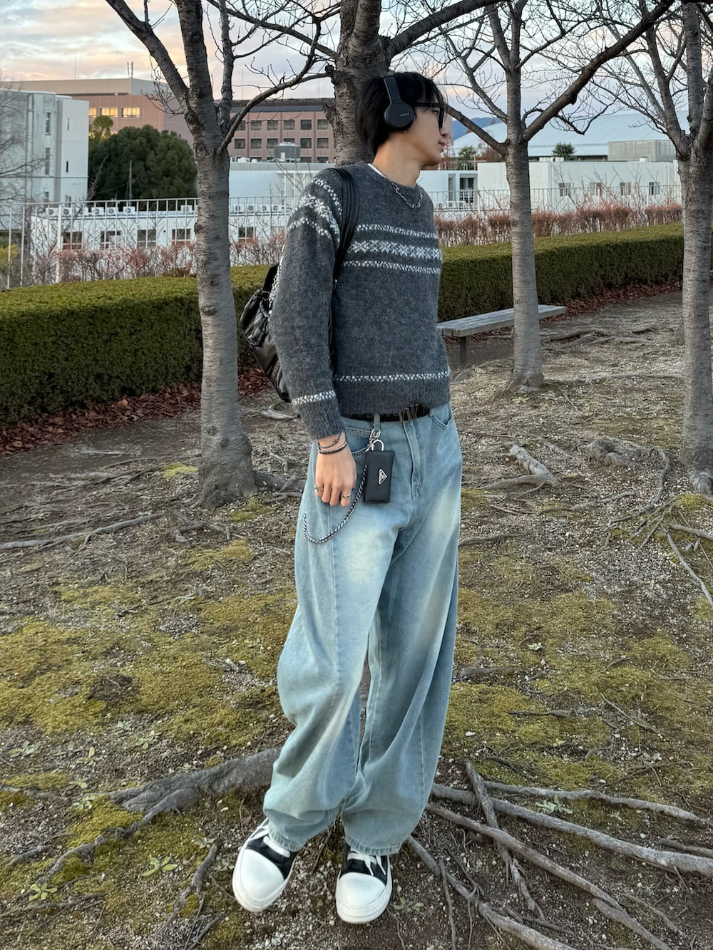 グレー系のニット/セーター、ブルー系のデニムパンツ、ブラック系のスニーカーを着用したメンズの冬コーディネートの2枚目の写真