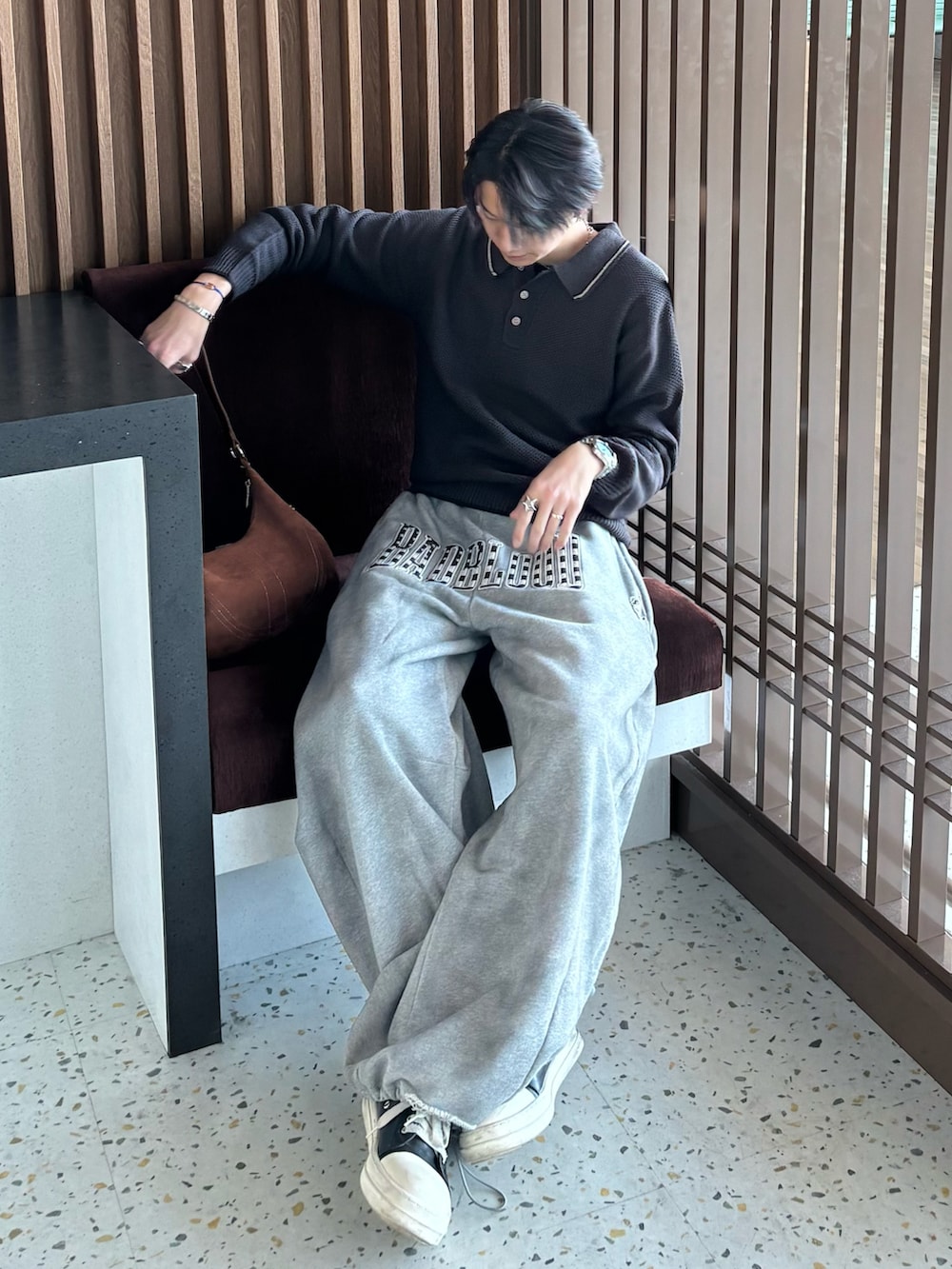 グレー系のポロシャツ、ブラウン系のショルダーバッグ、グレー系のスウェットパンツを着用したメンズの冬コーディネートの3枚目の写真