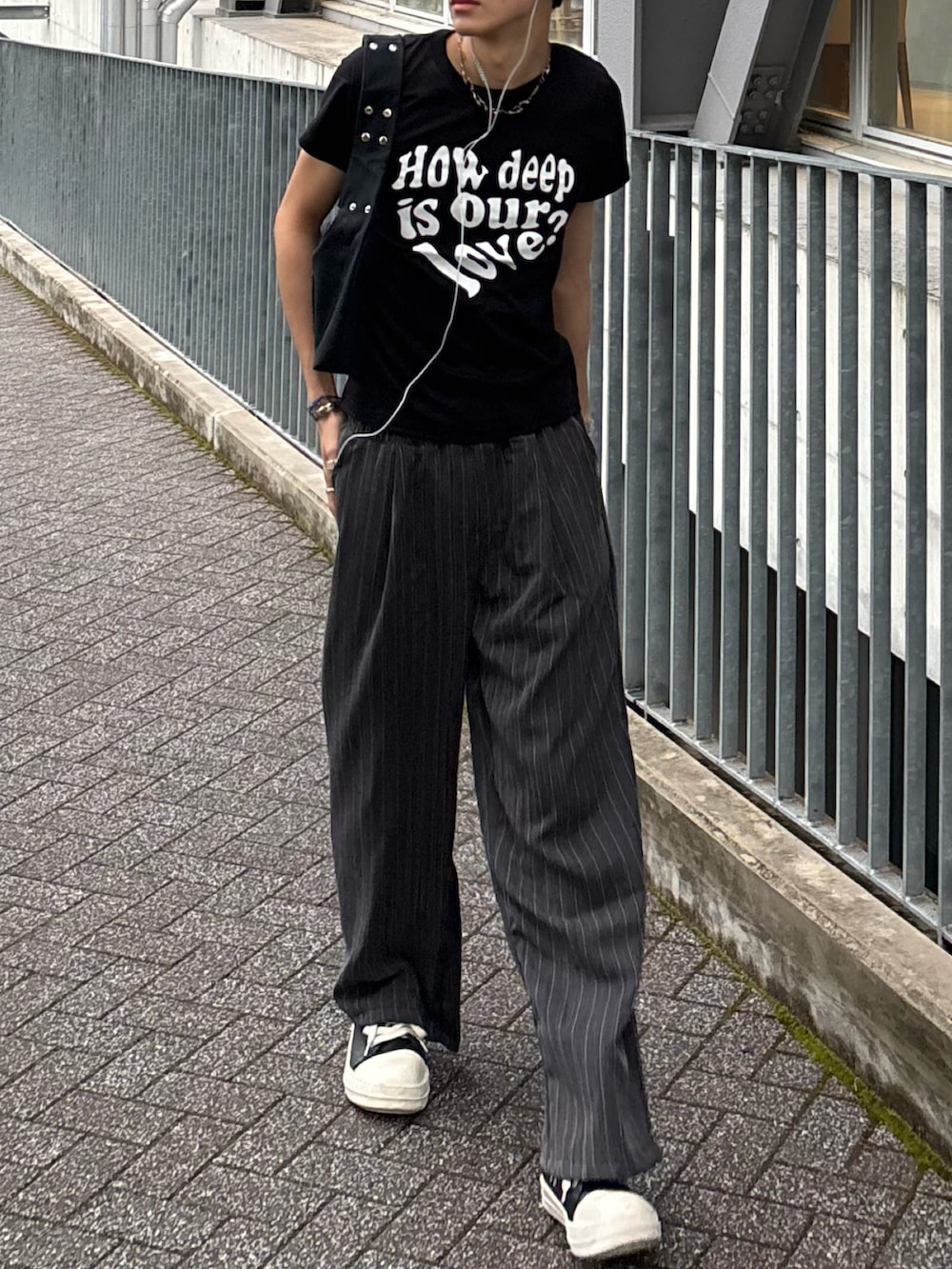 ブラック系のTシャツ/カットソー、ブラック系のショルダーバッグ、グレー系のスラックスを着用したメンズの春コーディネートの5枚目の写真