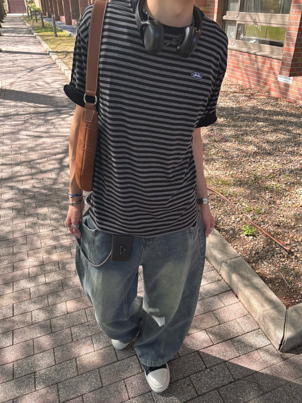 ブラック系のTシャツ/カットソー、ブルー系のデニムパンツ、ブラック系のスニーカーを着用したメンズの春コーディネートの5枚目の写真