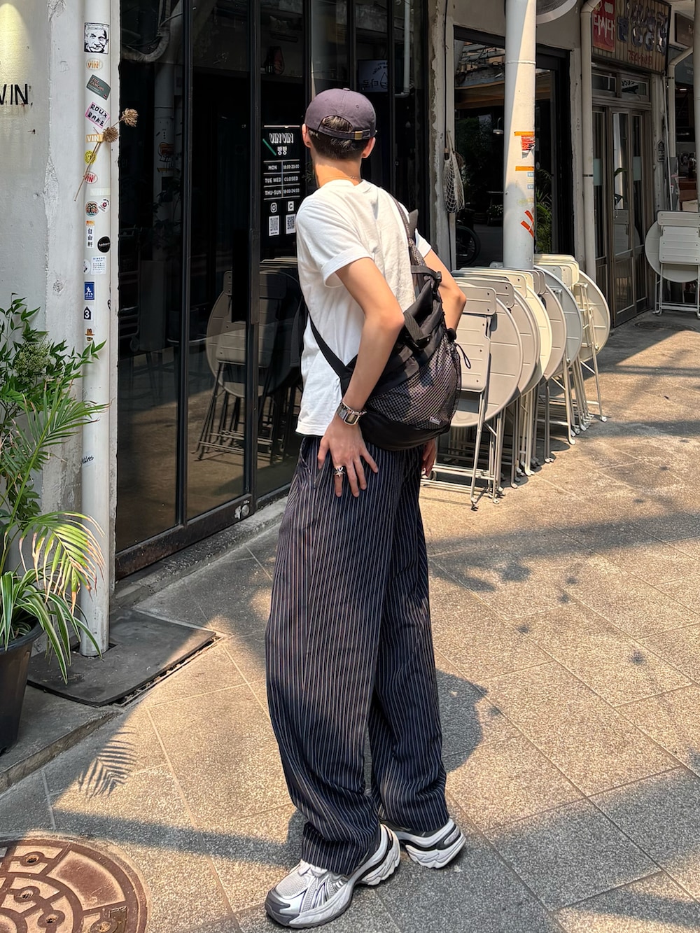 ホワイト系のTシャツ/カットソー、ブラック系のスラックス、ホワイト系のスニーカーを着用したメンズの春コーディネートの3枚目の写真