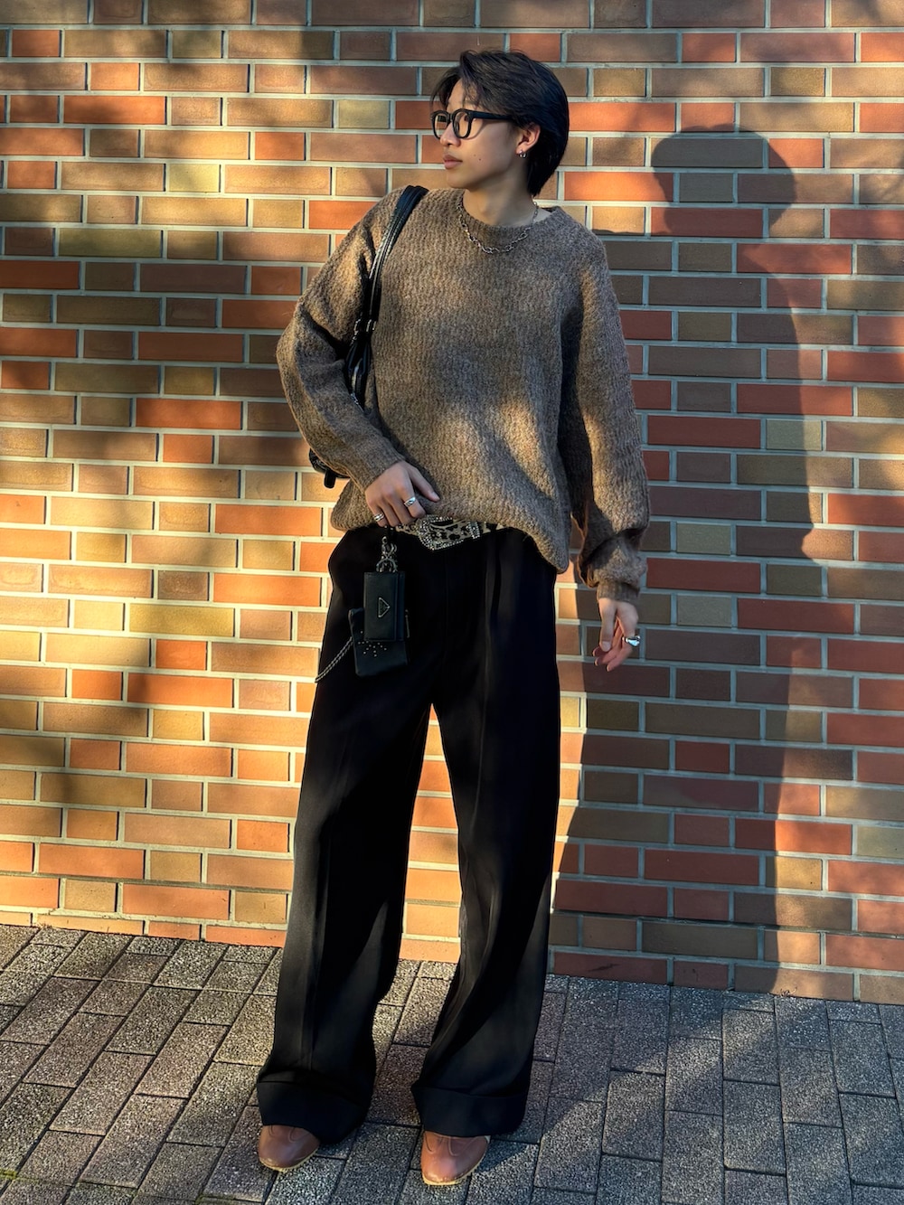 ブラウン系のニット/セーター、ブラック系のトートバッグ、ブラック系のスラックスを着用したメンズの秋コーディネートの2枚目の写真