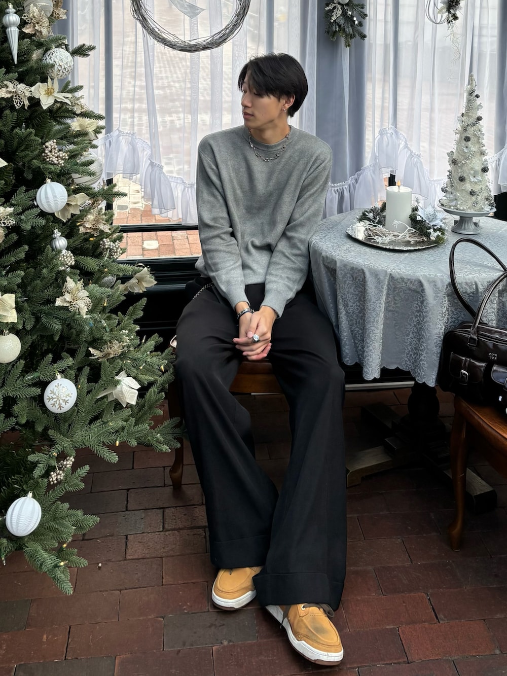 グレー系のニット/セーター、ブラウン系のショルダーバッグ、ブラック系のスラックスを着用したメンズの冬コーディネートの2枚目の写真