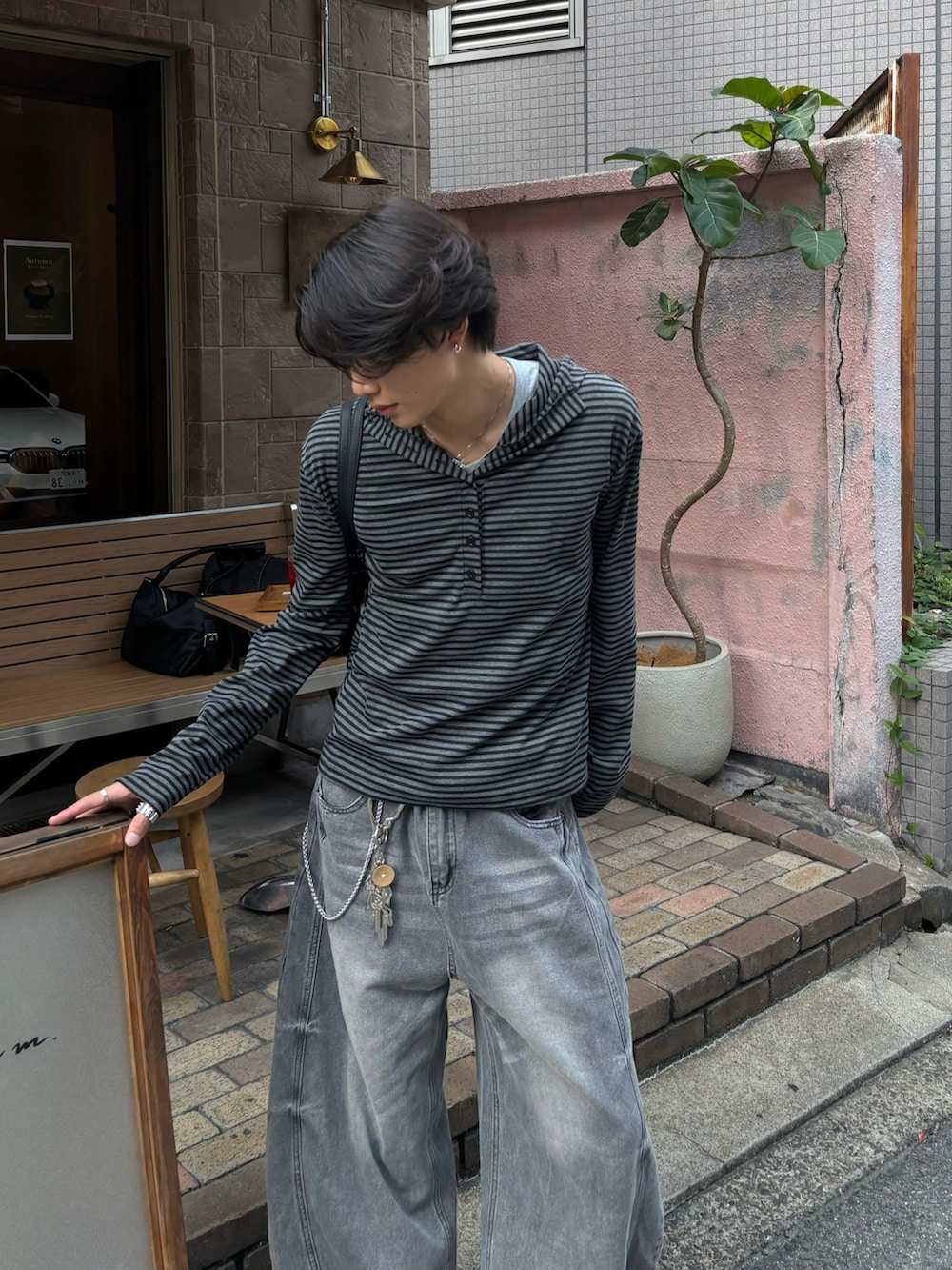 ブラック系のパーカー、ブラック系のショルダーバッグ、グレー系のデニムパンツを着用したメンズの秋コーディネートの4枚目の写真