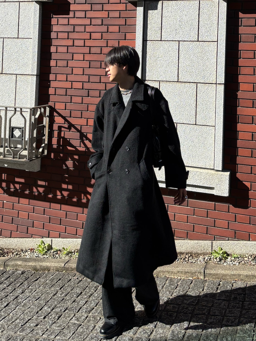 ブラック系のチェスターコート、ブラック系のデニムパンツ、ブラック系のドレスシューズを着用したメンズの冬コーディネートの3枚目の写真