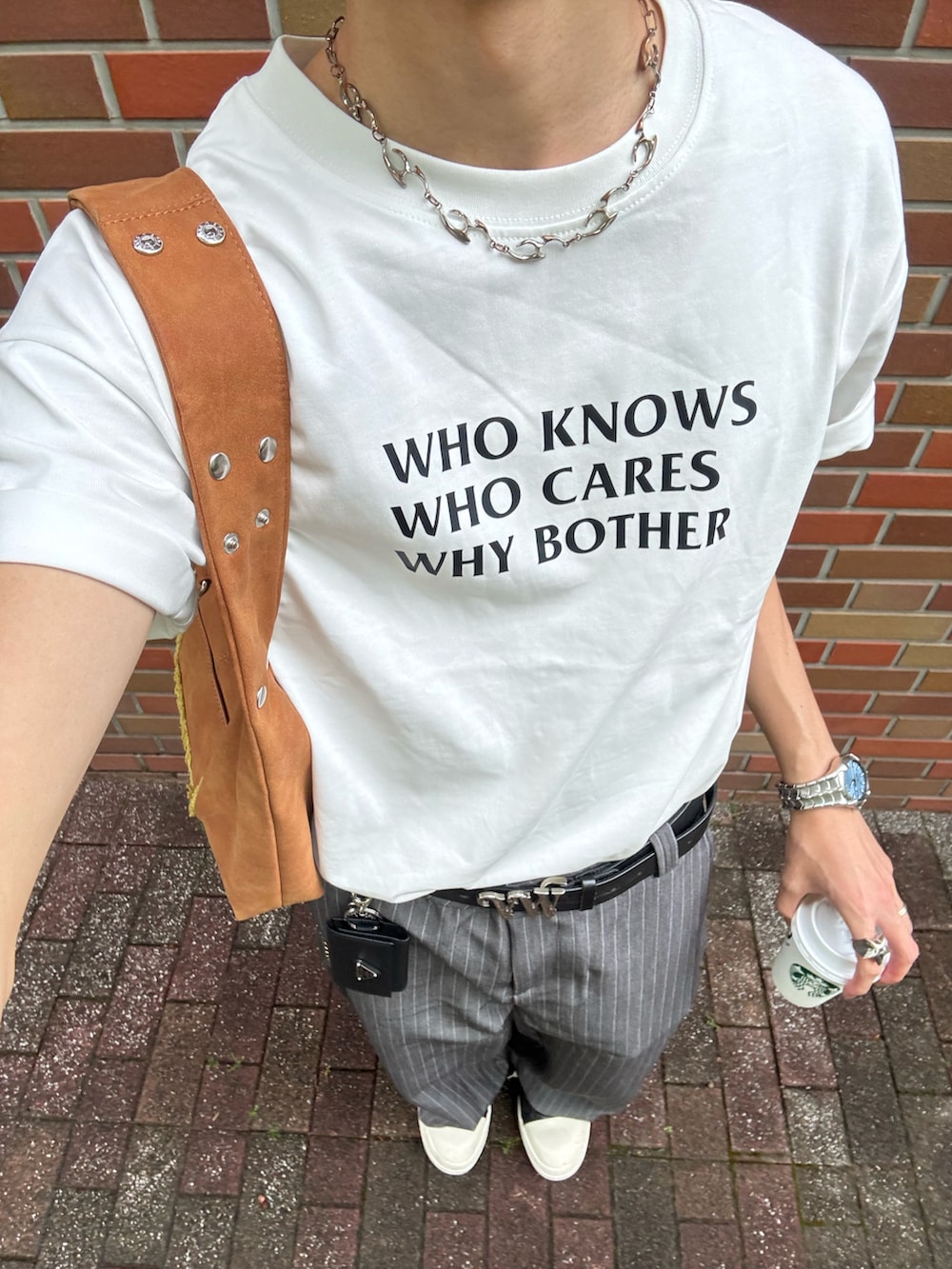 ホワイト系のTシャツ/カットソー、グレー系のスラックス、ブラック系のスニーカーを着用したメンズの春コーディネートの3枚目の写真
