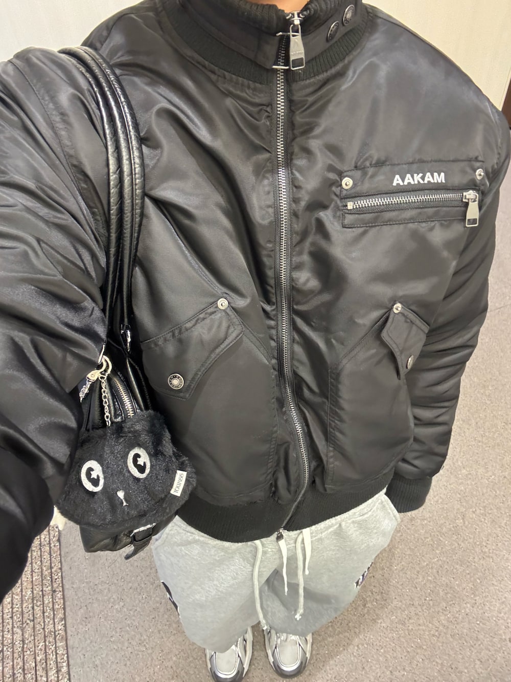 ブラック系のジャケット/アウター、グレー系のニット/セーター、グレー系のスウェットパンツを着用したメンズの冬コーディネートの2枚目の写真