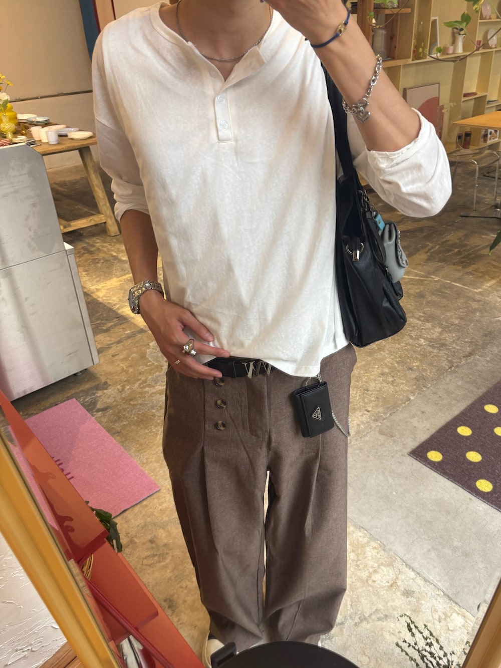 ホワイト系のTシャツ/カットソー、ブラウン系のスラックス、ブラック系のスニーカーを着用したメンズの夏コーディネートの5枚目の写真