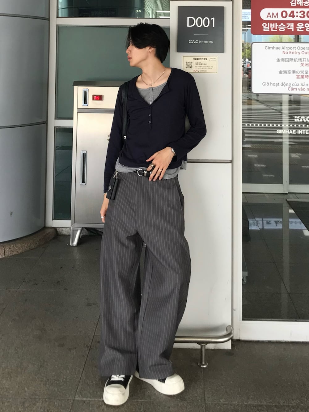 ブルー系のTシャツ/カットソー、グレー系のスラックス、ブラック系のスニーカーを着用したメンズの秋コーディネートの2枚目の写真