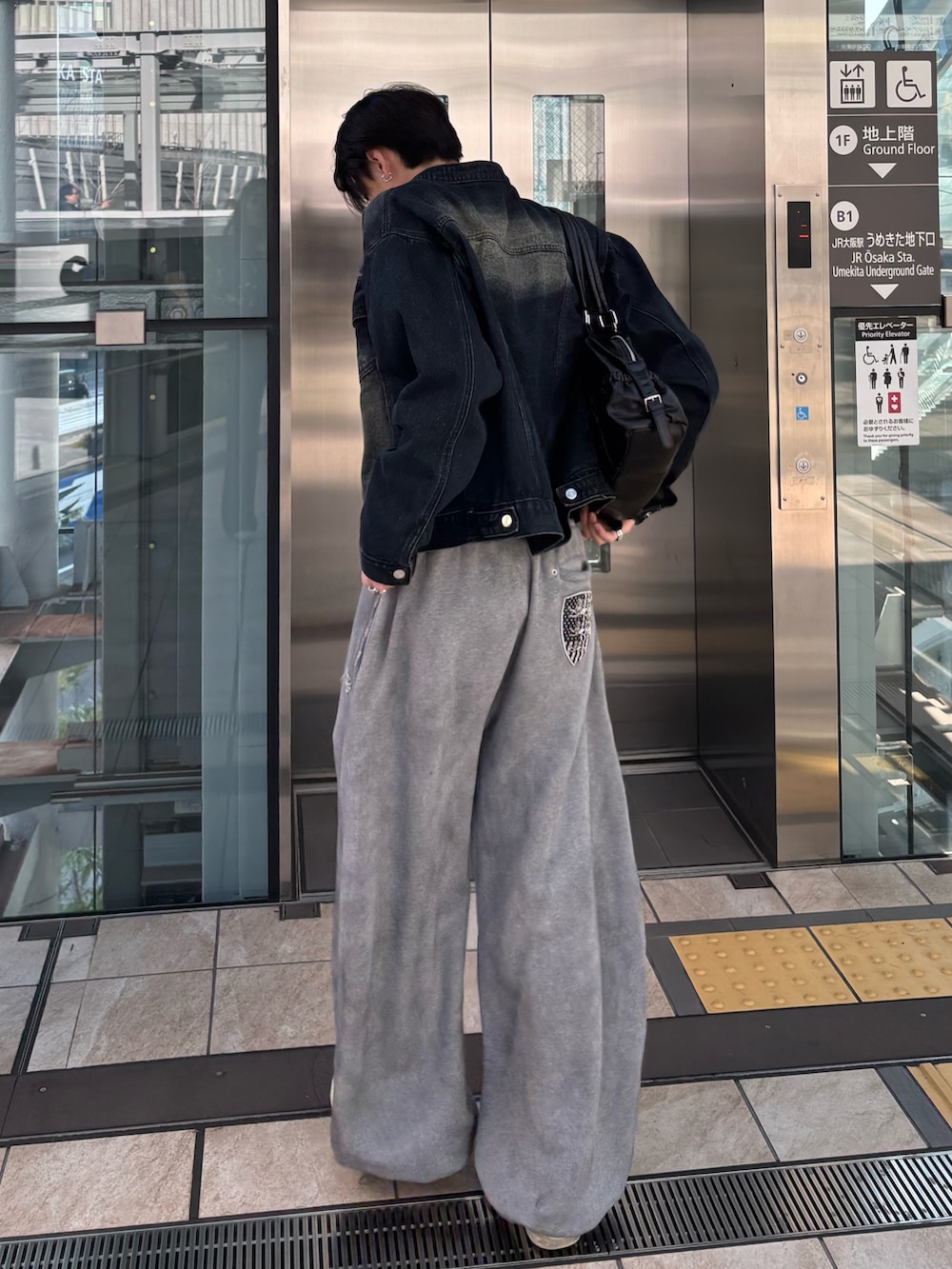 ブルー系のデニムジャケット、その他のTシャツ/カットソー、ブラック系のショルダーバッグを着用したメンズの冬コーディネートの3枚目の写真