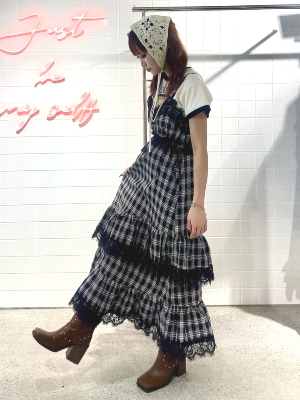 ブラック系のブーツ、ブラック系のワンピース、ホワイト系のTシャツ/カットソーを着用したレディースの夏コーディネートの3枚目の写真