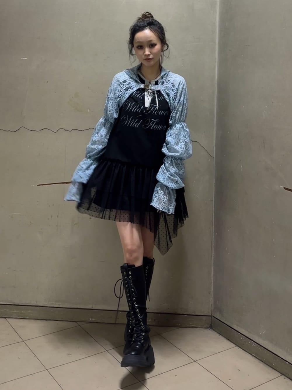 ブラック系のブーツ、ブラック系のワンピース、ブルー系のカーディガン/ボレロを着用したレディースの春コーディネートの2枚目の写真