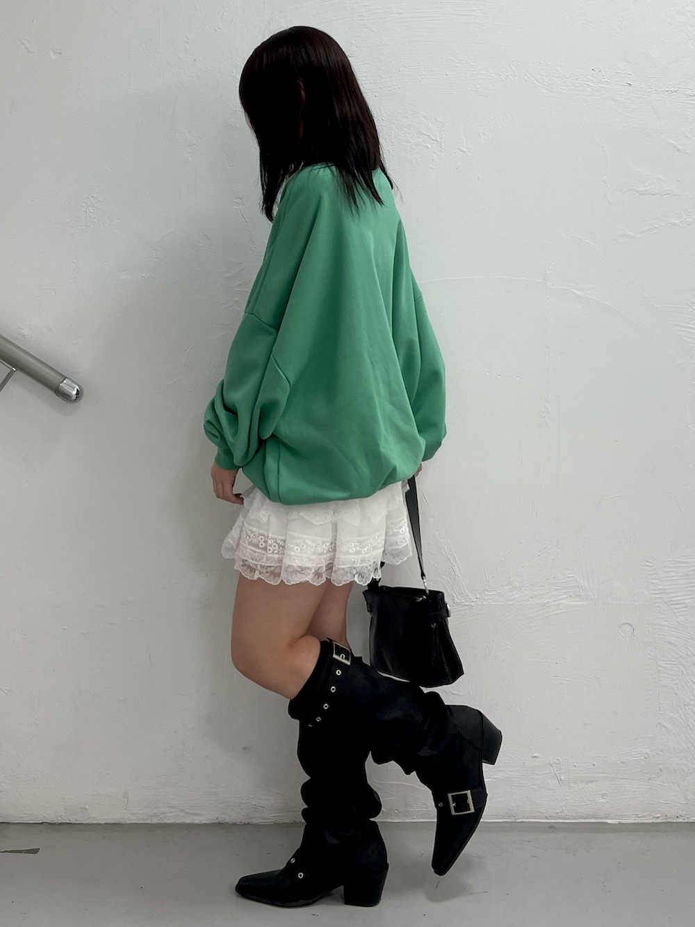 グリーン系のスウェット、ホワイト系のその他パンツ、ブラック系のハンドバッグを着用したレディースの冬コーディネートの3枚目の写真