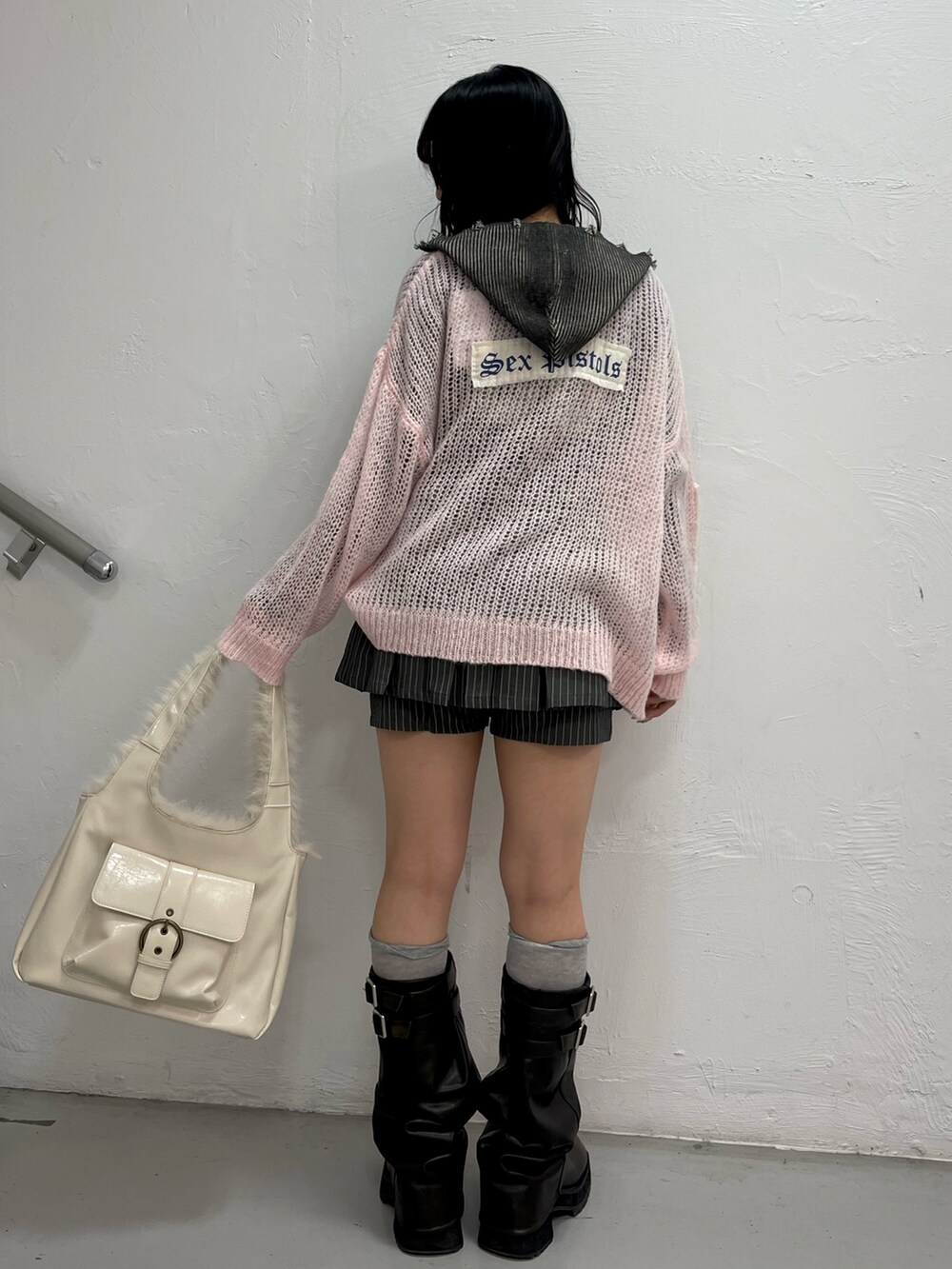 ピンク系のニット/セーター、グレー系のスカート、ブラック系のニット/セーターを着用したレディースの秋コーディネートの3枚目の写真