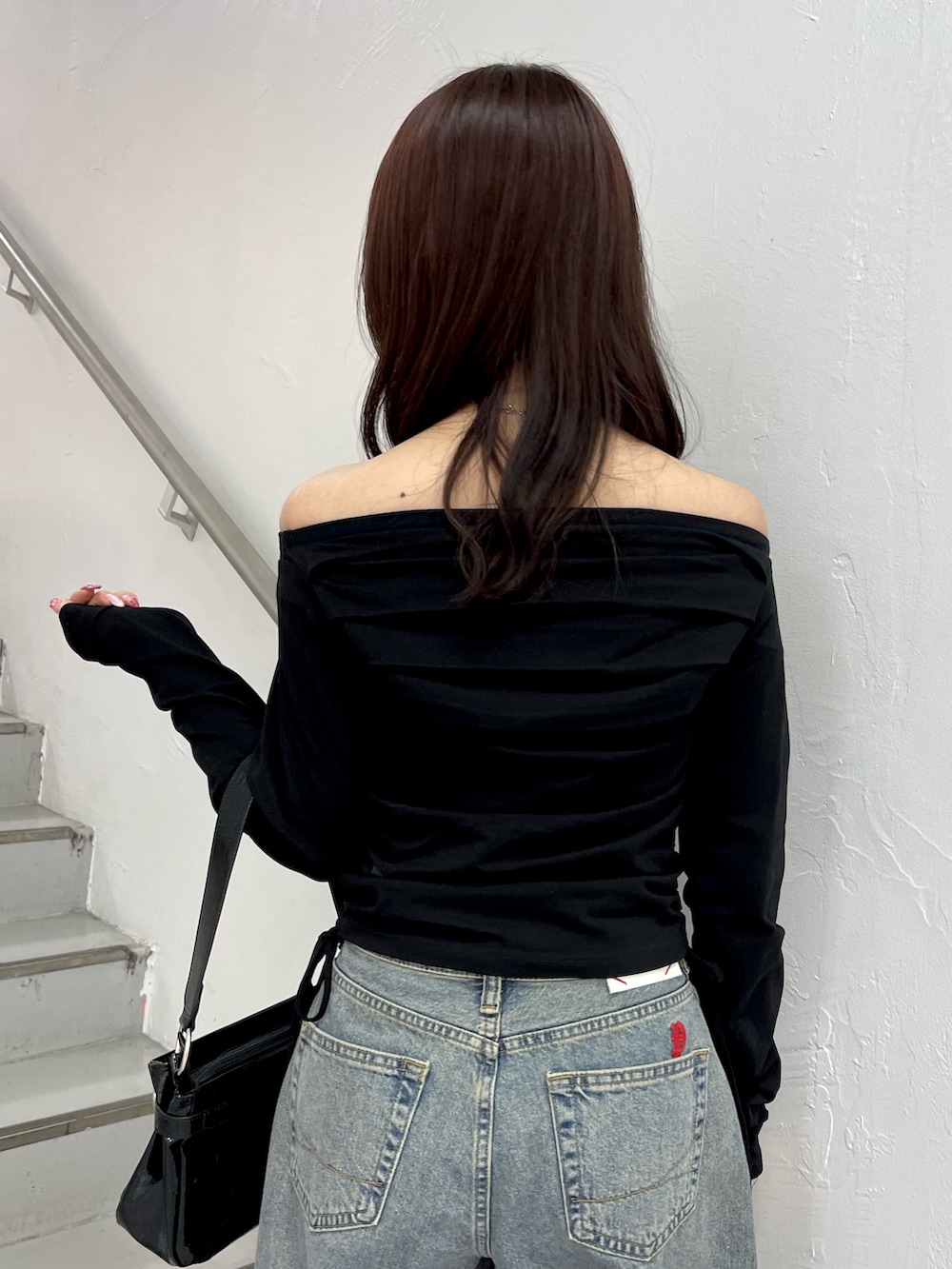 ブラック系のTシャツ/カットソー、ブルー系のデニムパンツ、ブラック系のハンドバッグを着用したレディースの冬コーディネートの7枚目の写真