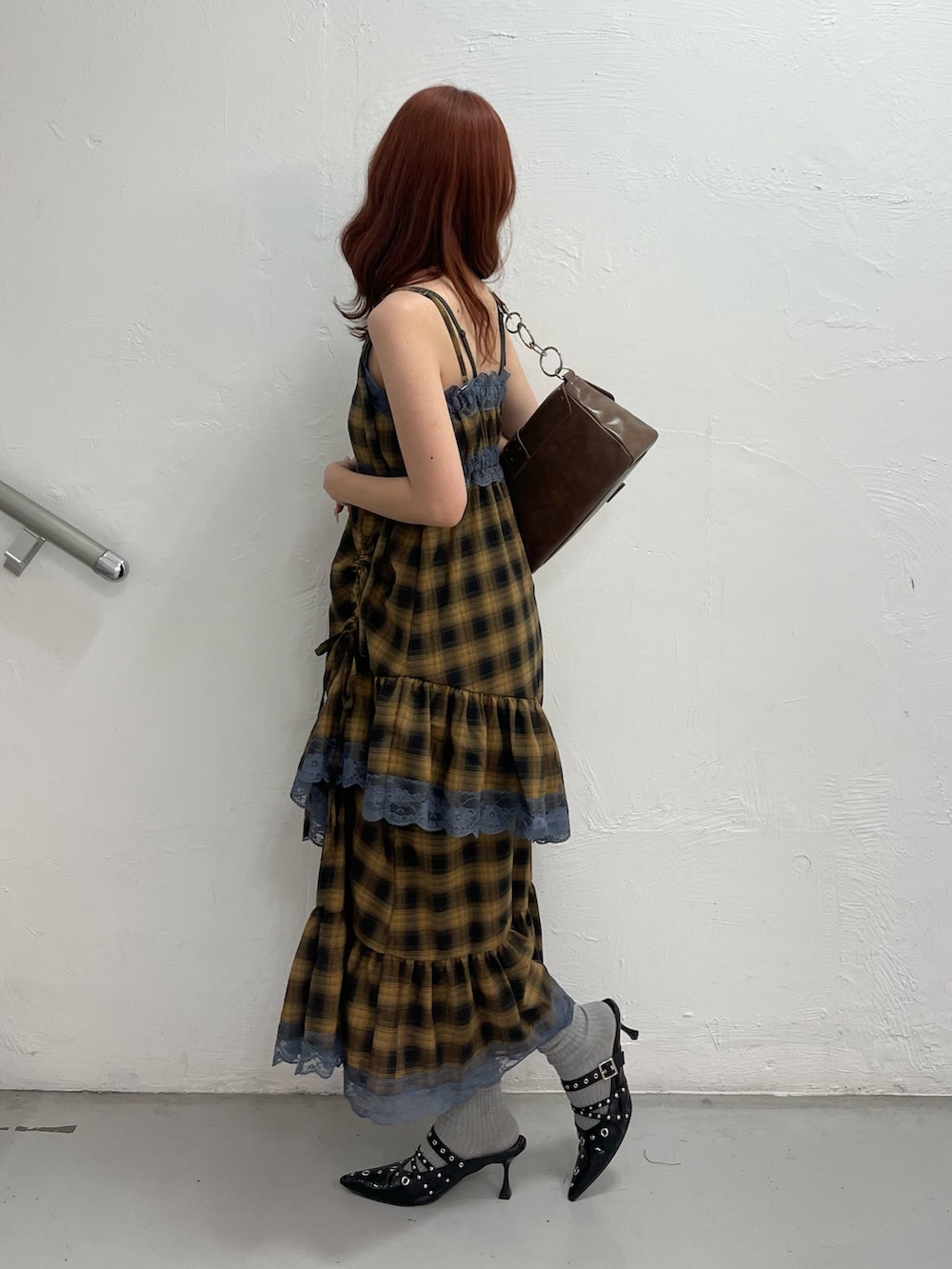 イエロー系のワンピース、ブラック系のパンプス、ブラウン系のハンドバッグを着用したレディースの夏コーディネートの3枚目の写真