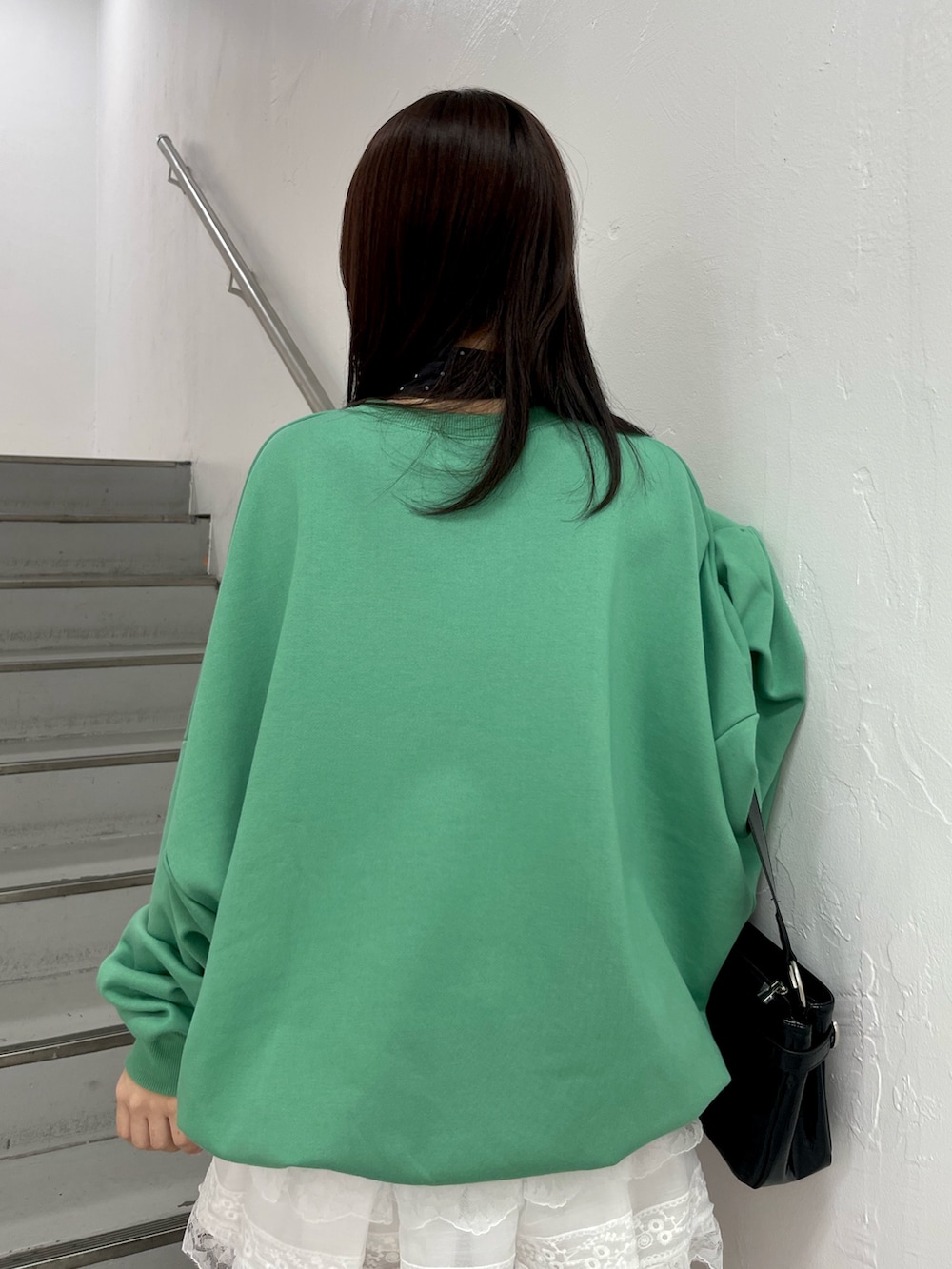 グリーン系のスウェット、ホワイト系のその他パンツ、ブラック系のハンドバッグを着用したレディースの冬コーディネートの7枚目の写真