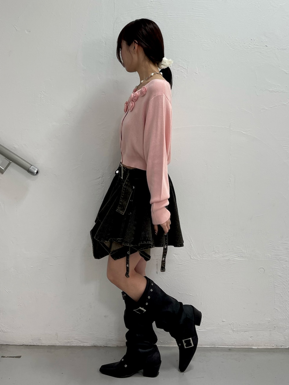 ピンク系のニット/セーター、ブラック系のデニムスカート、ブラック系のブーツを着用したレディースの春コーディネートの3枚目の写真