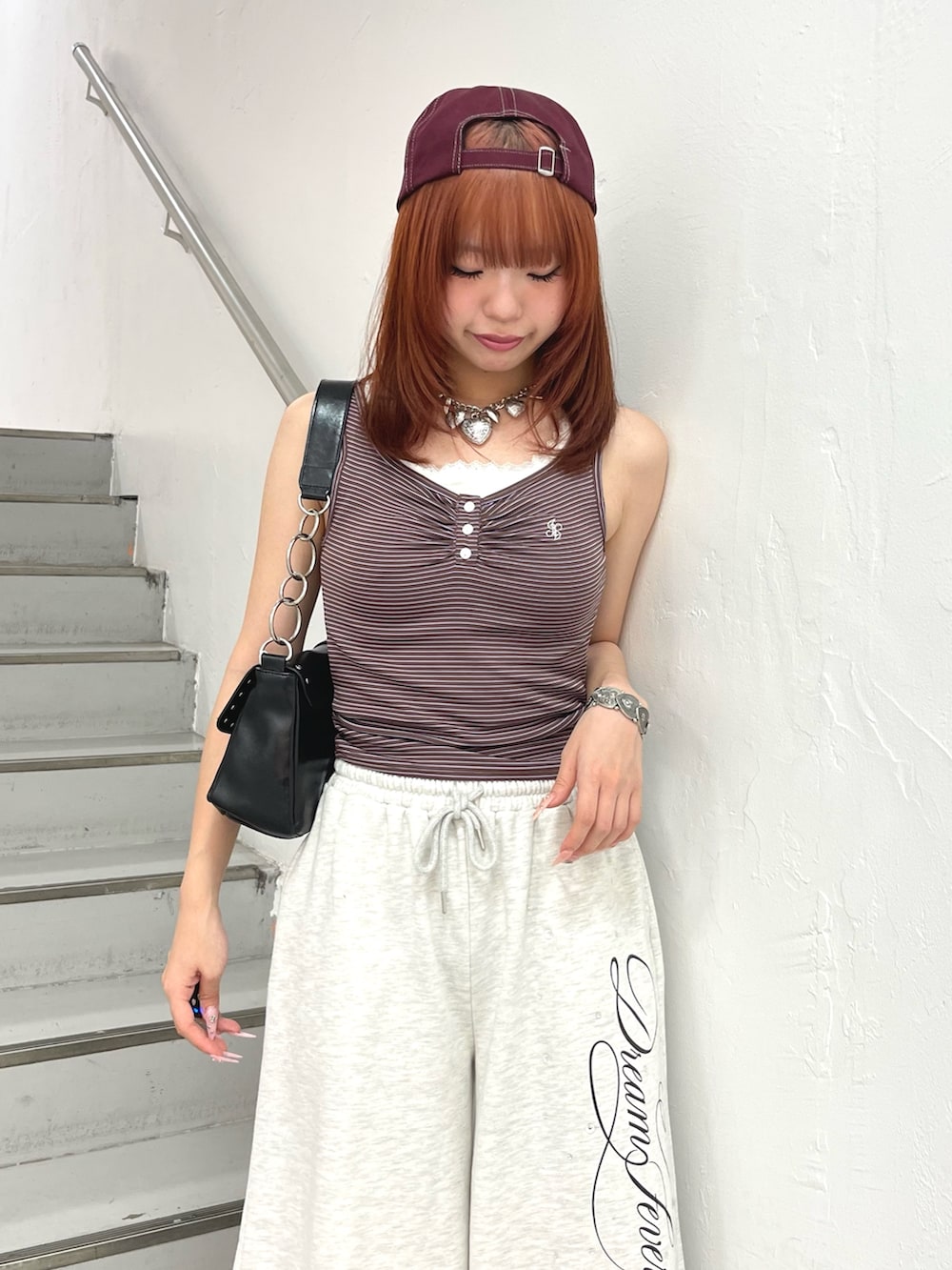 ブラウン系のタンクトップ、ブラック系のハンドバッグ、グレー系のその他パンツを着用したレディースの夏コーディネートの5枚目の写真