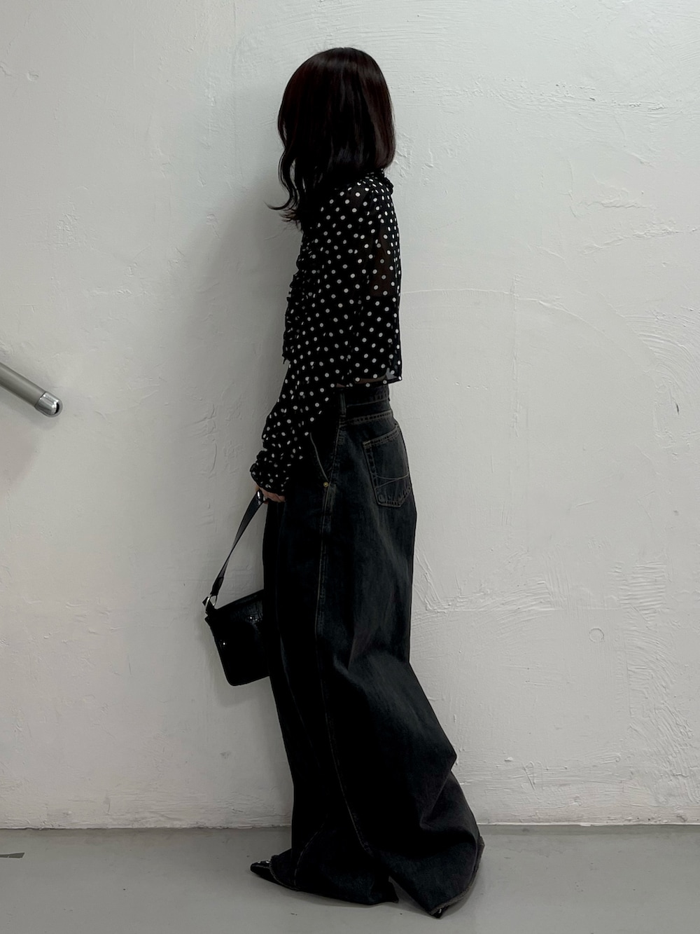 ブラック系のデニムパンツ、ブラック系のハンドバッグ、ブラック系のパンプスを着用したレディースの春コーディネートの3枚目の写真