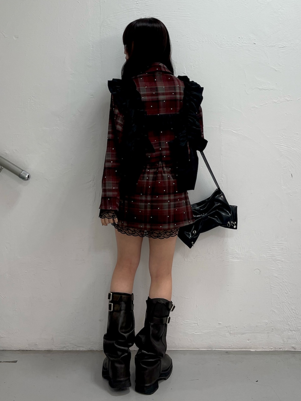 レッド系のテーラードジャケット、レッド系のスカート、ブラック系のショルダーバッグを着用したレディースの冬コーディネートの3枚目の写真