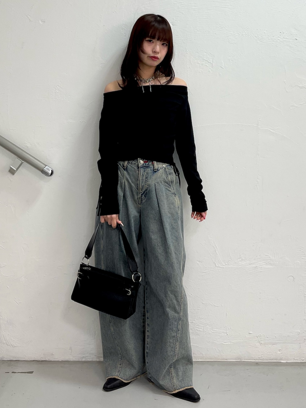 ブラック系のTシャツ/カットソー、ブルー系のデニムパンツ、ブラック系のハンドバッグを着用したレディースの冬コーディネートの2枚目の写真