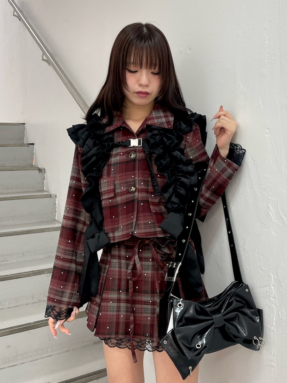 レッド系のテーラードジャケット、レッド系のスカート、ブラック系のショルダーバッグを着用したレディースの冬コーディネートの4枚目の写真