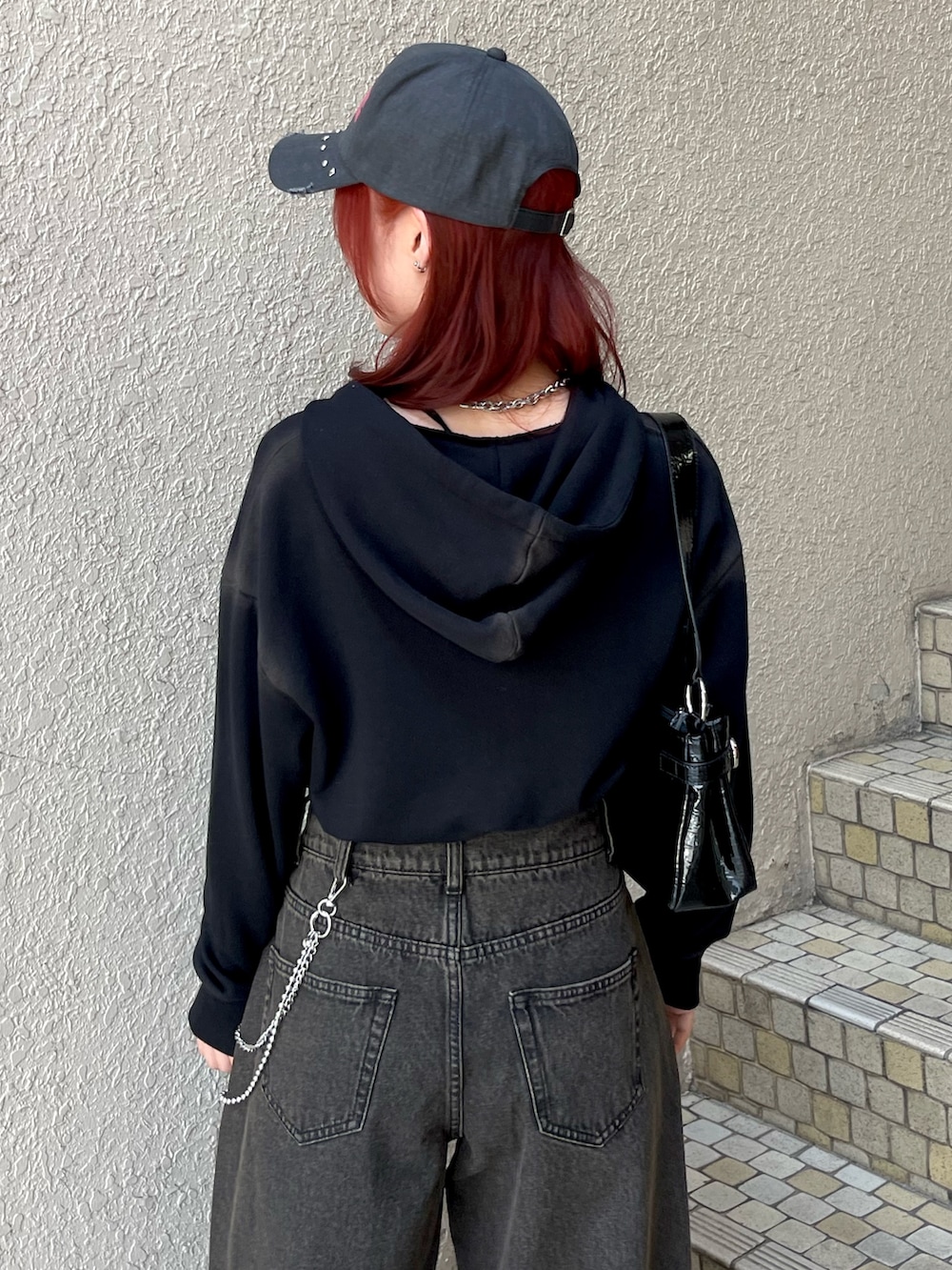 ブラック系のパーカー、ブラック系のデニムパンツ、ブラック系のハンドバッグを着用したレディースの春コーディネートの7枚目の写真