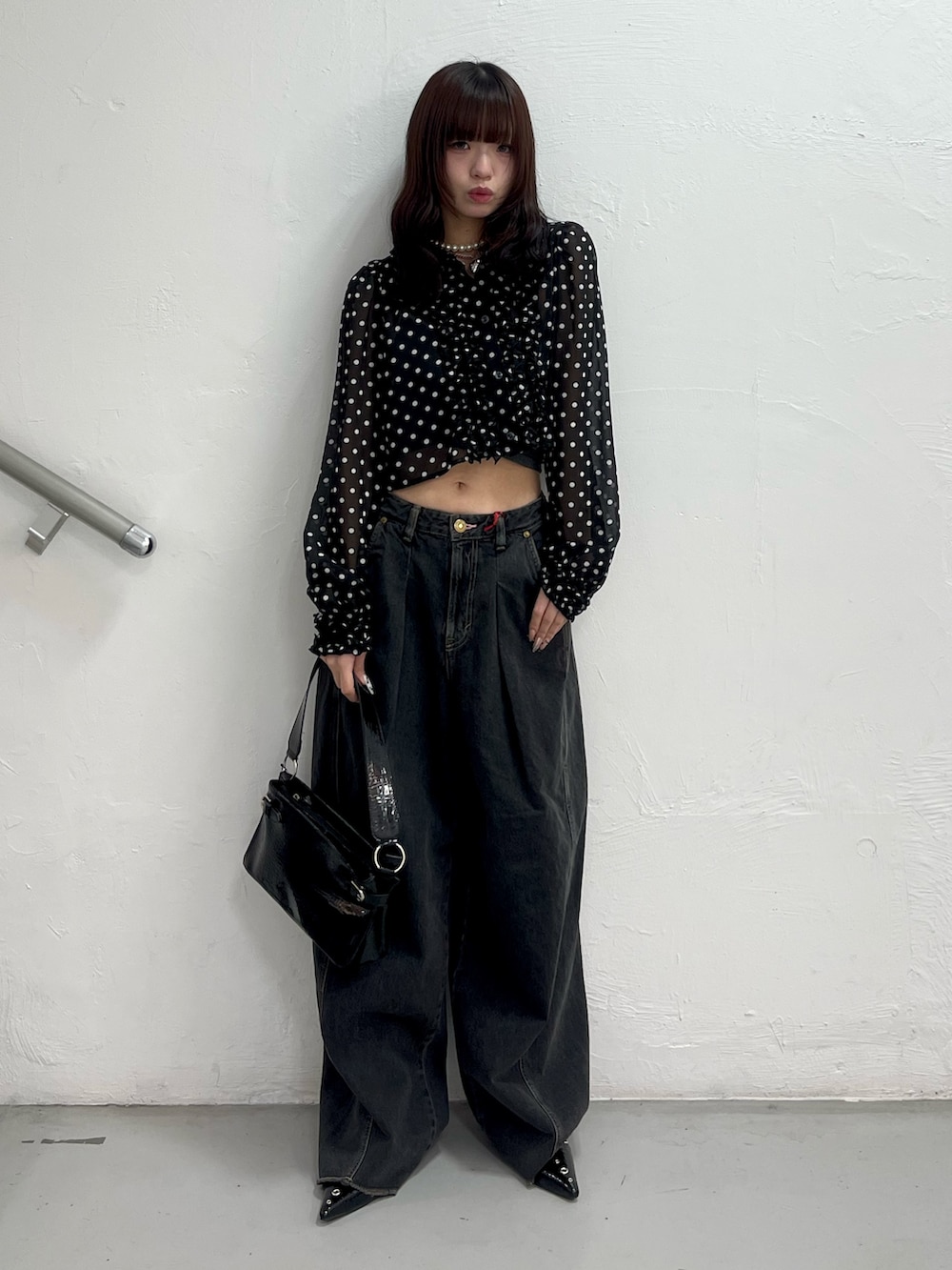 ブラック系のデニムパンツ、ブラック系のハンドバッグ、ブラック系のパンプスを着用したレディースの春コーディネートの2枚目の写真