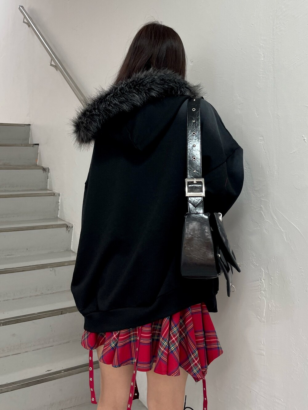 ブラック系のパーカー、レッド系のスカート、ブラック系のショルダーバッグを着用したレディースの冬コーディネートの6枚目の写真