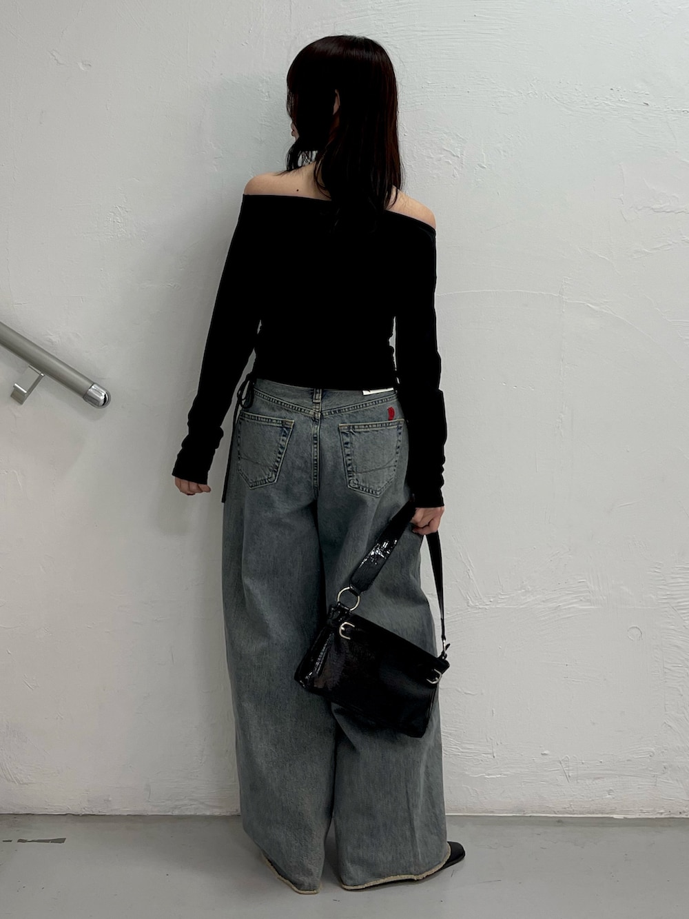 ブラック系のTシャツ/カットソー、ブルー系のデニムパンツ、ブラック系のハンドバッグを着用したレディースの冬コーディネートの4枚目の写真