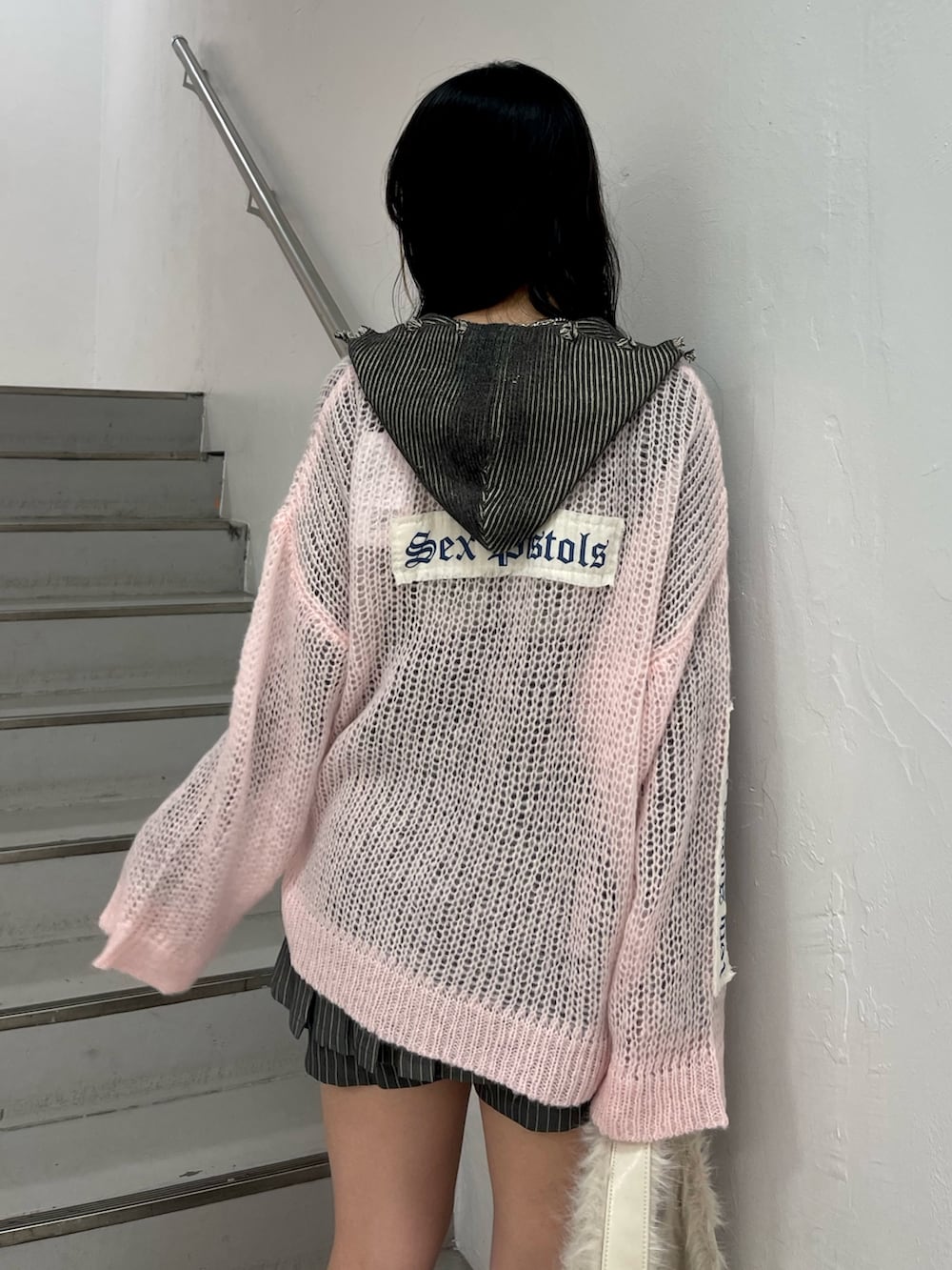 ピンク系のニット/セーター、グレー系のスカート、ブラック系のニット/セーターを着用したレディースの秋コーディネートの6枚目の写真