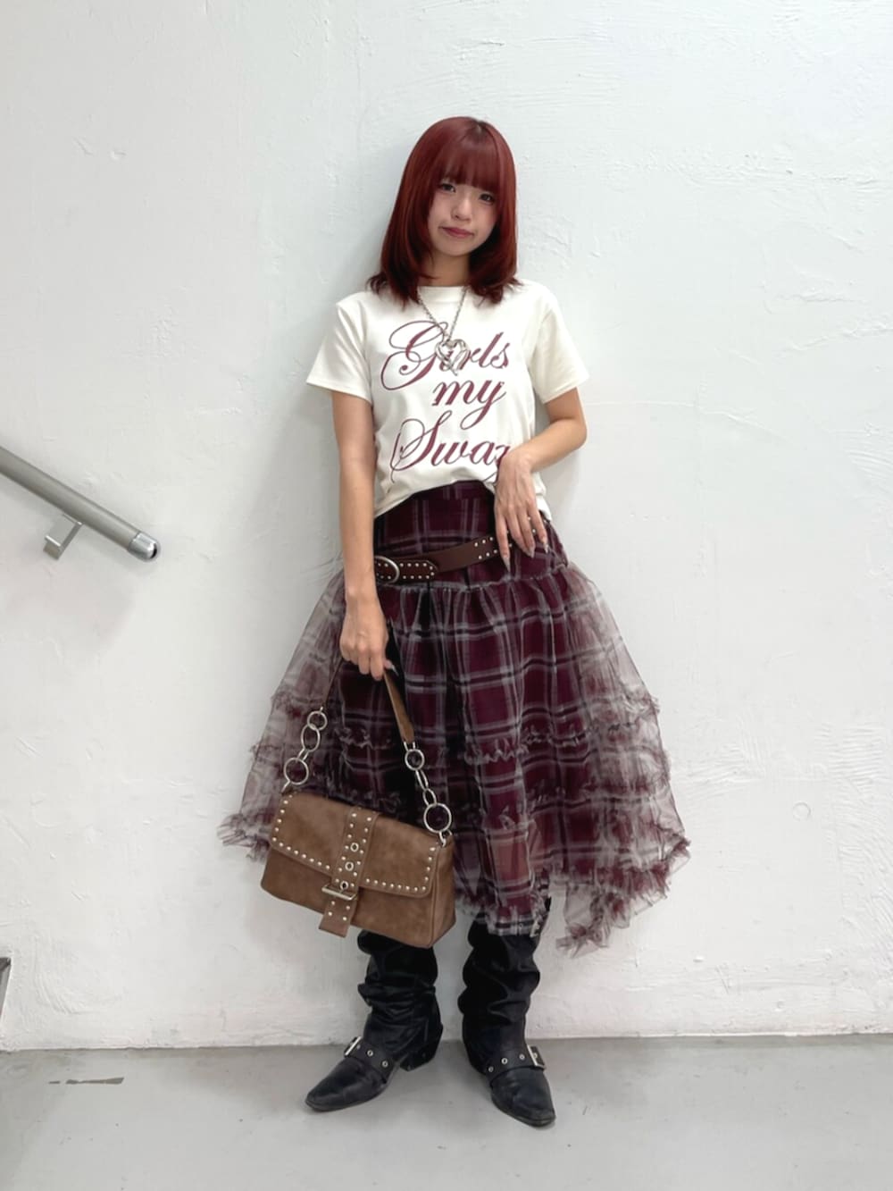 ブラウン系のハンドバッグ、ブラック系のブーツ、ホワイト系のTシャツ/カットソーを着用したレディースの夏コーディネートの2枚目の写真
