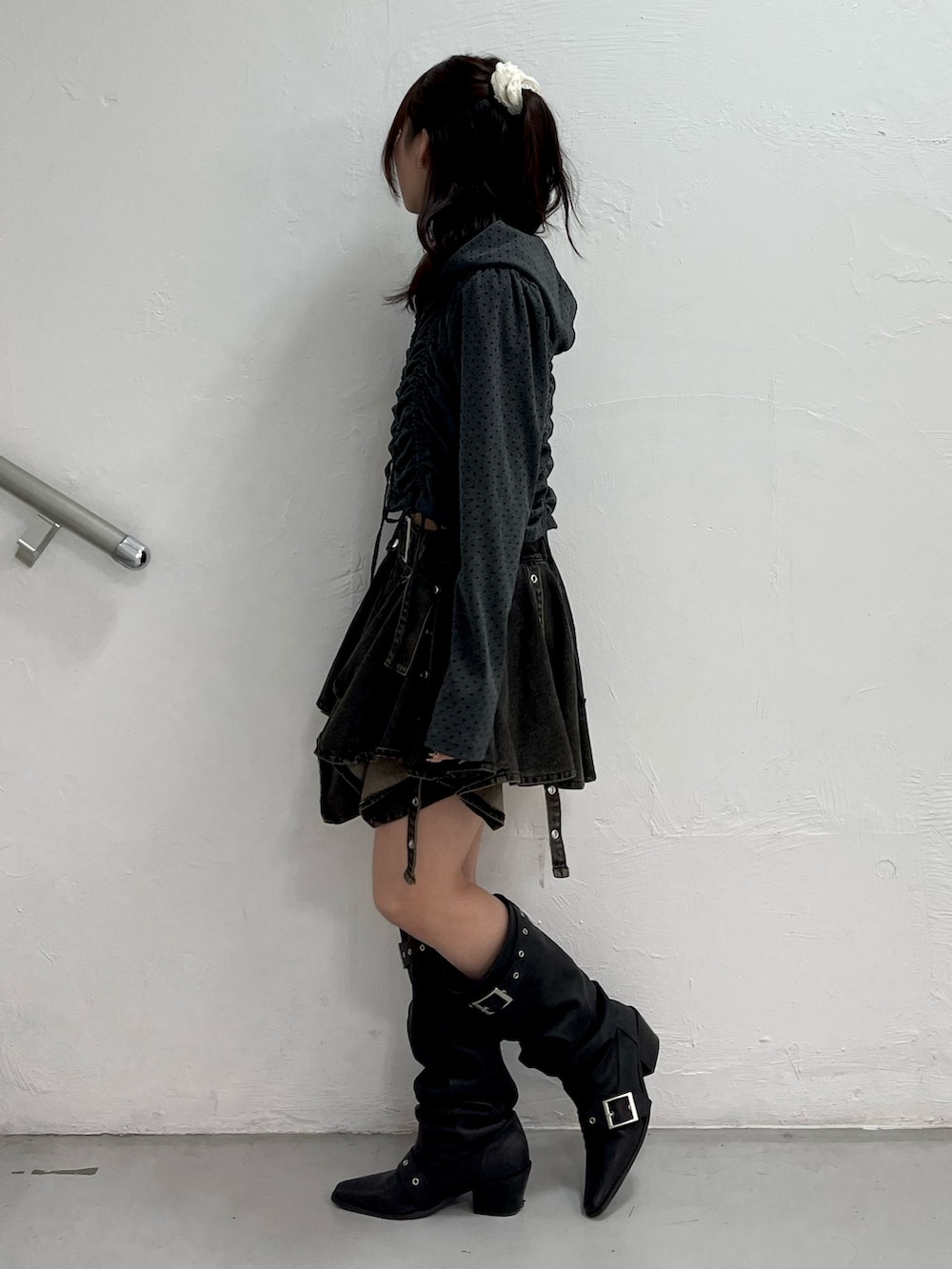 ブラック系のパーカー、ブラック系のデニムスカート、ブラック系のブーツを着用したレディースの春コーディネートの3枚目の写真