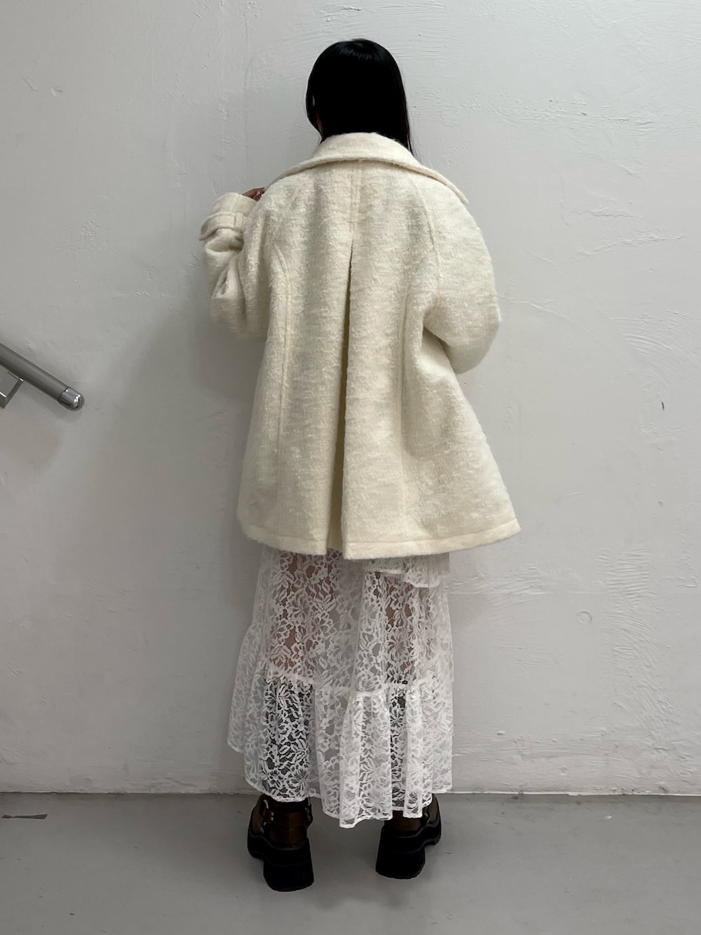 ホワイト系のステンカラーコート、グレー系のカーディガン/ボレロ、ホワイト系のスカートを着用したレディースの秋コーディネートの4枚目の写真